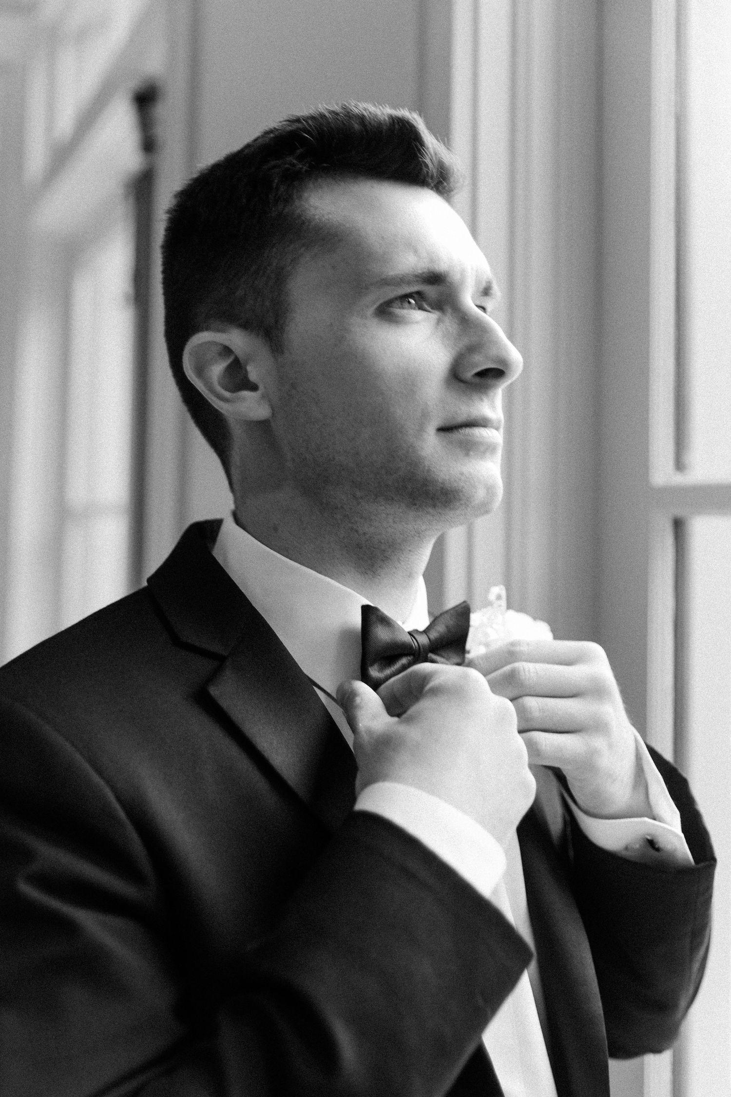 Black and white portrait series showing a person adjusting their bowtie before a formal event.