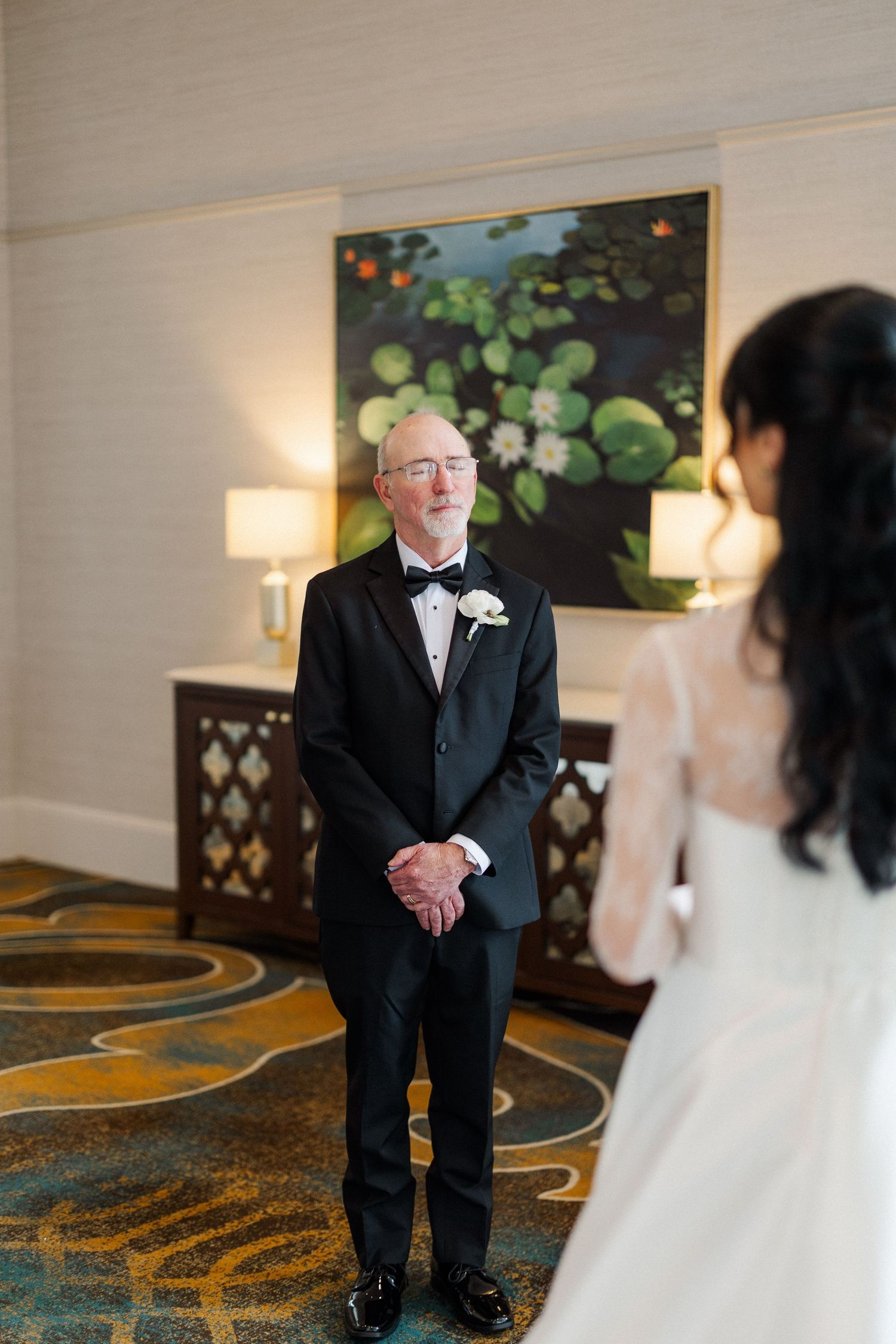 Emotional father in tuxedo sees bride daughter for the first time on wedding day.