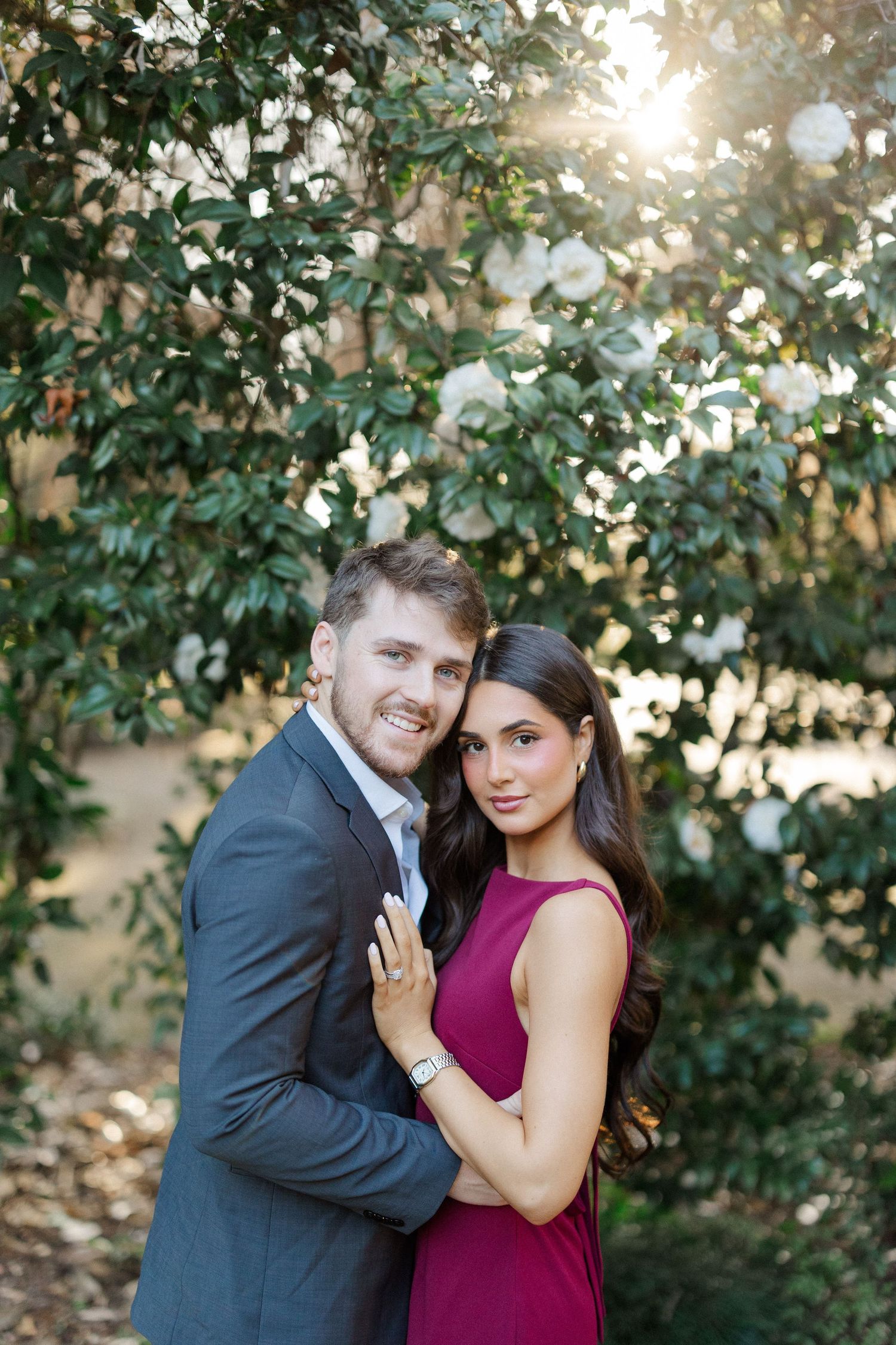 A couple shares an intimate moment during their engagement photoshoot in a lush garden setting.