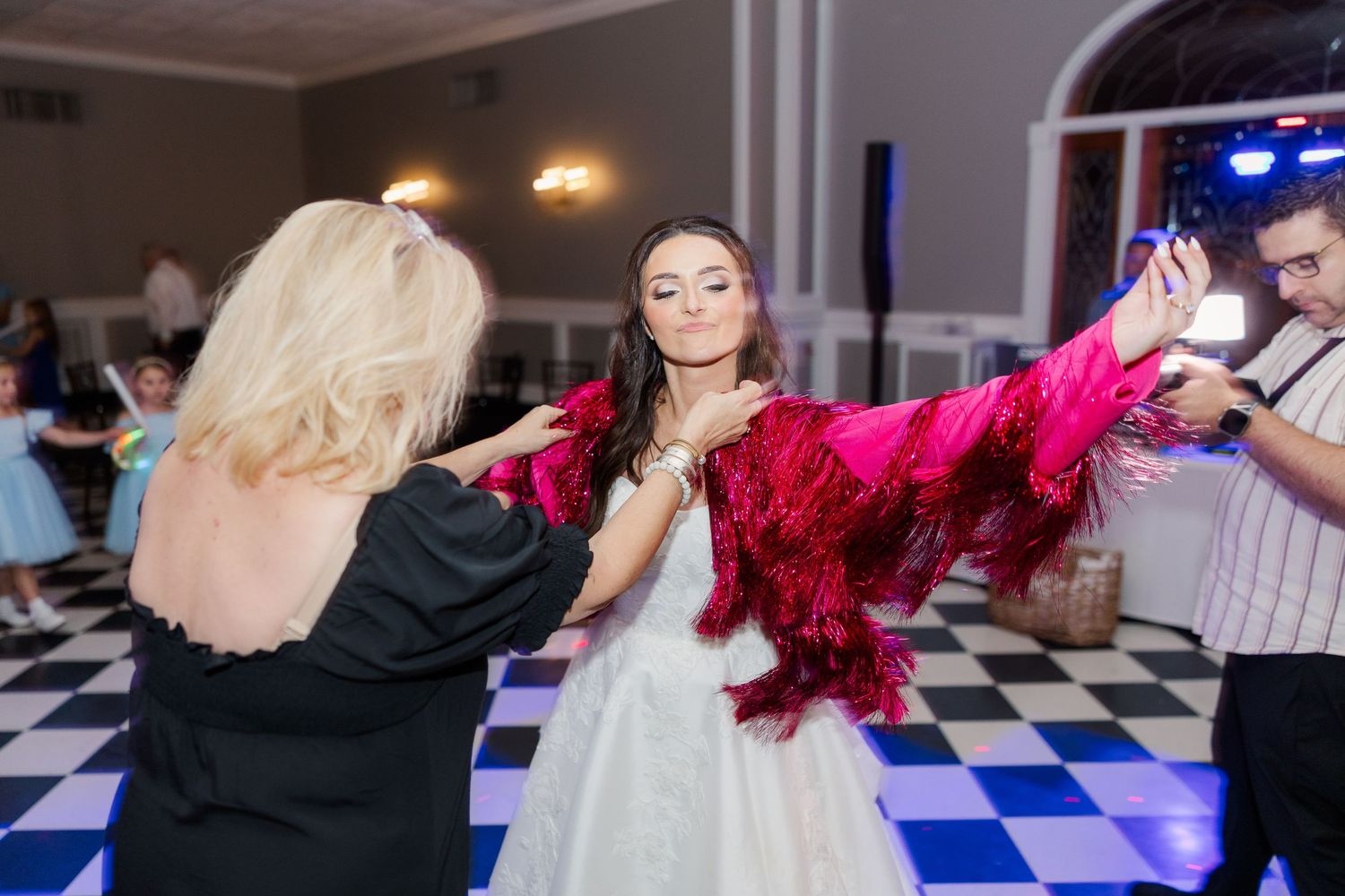 Wedding reception dance floor with guests celebrating in black and white checkered ballroom.