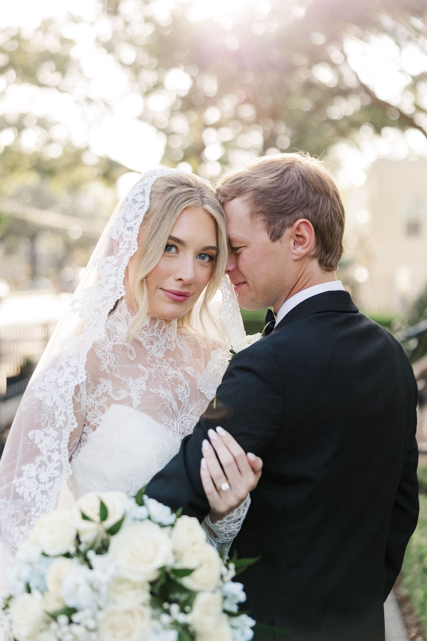 Romantic wedding portraits with white bouquet and lace veil in soft natural light.