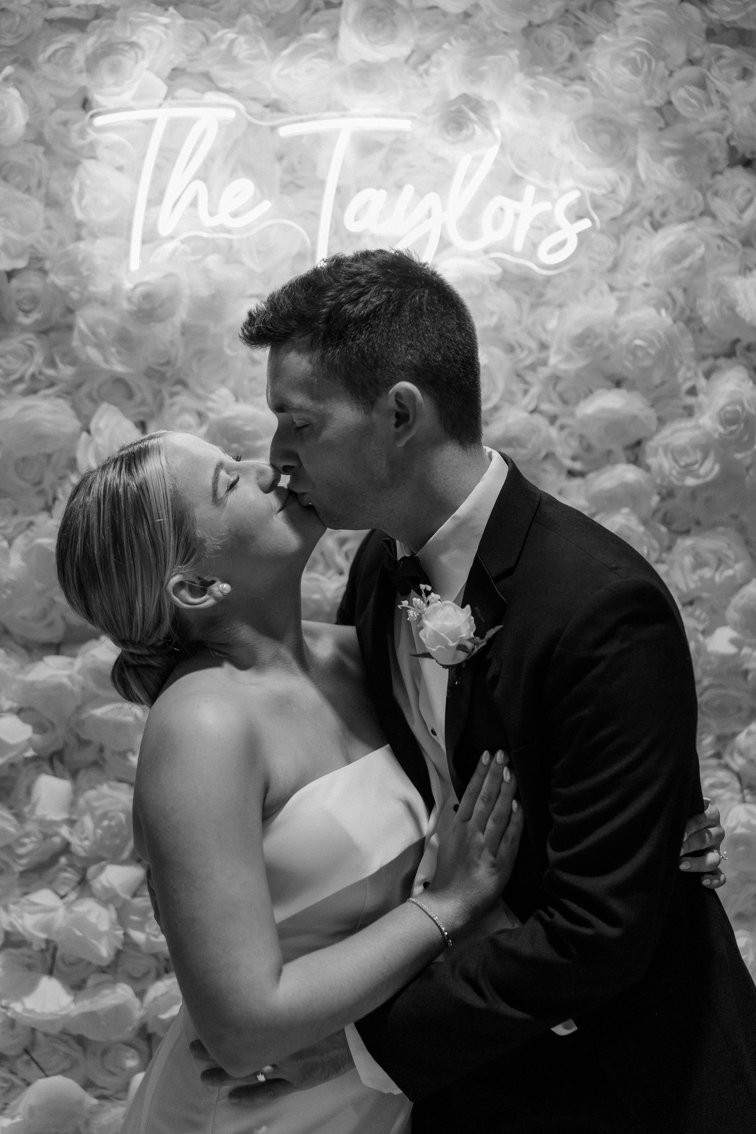 A romantic black and white photo series of a couple kissing against a floral backdrop.
