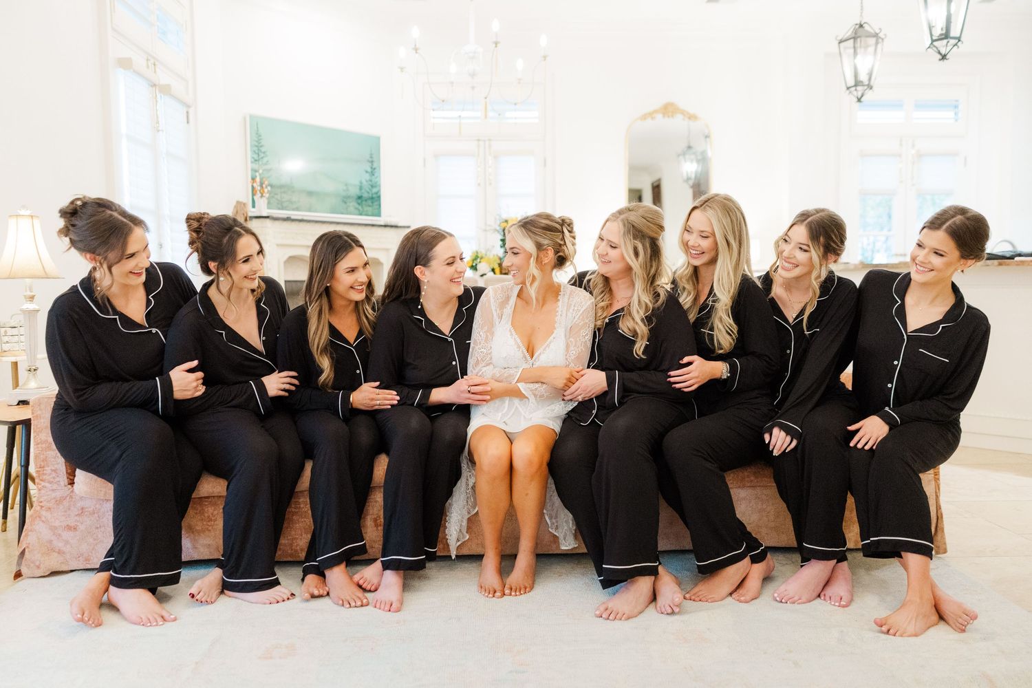 A group of dancers in black leotards sit in a row on a studio floor during dance class practice.