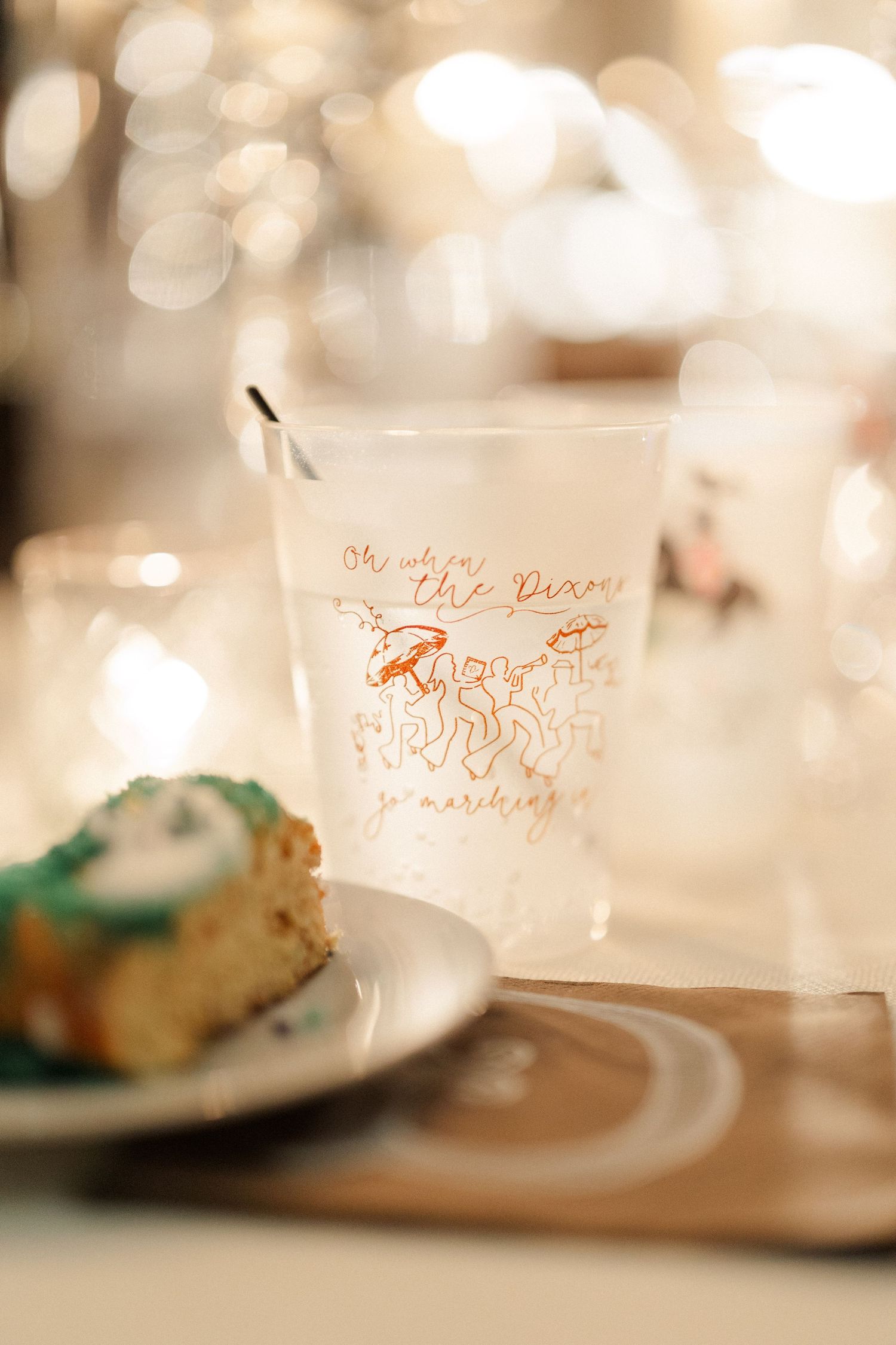 A decorative wedding reception glass with rose gold details sits beside a plated dessert.