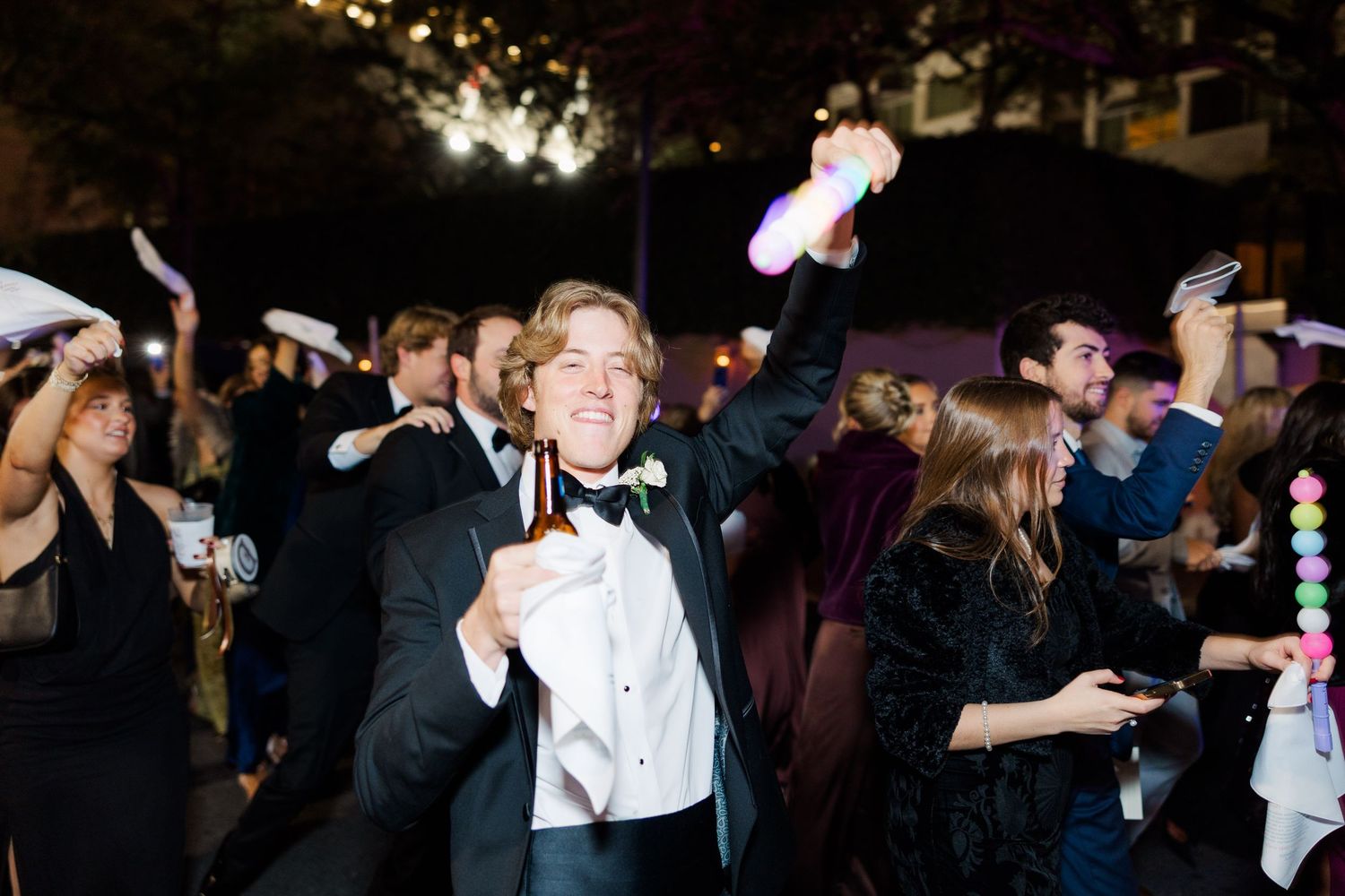 Wedding guests dancing and celebrating during a nighttime reception party.