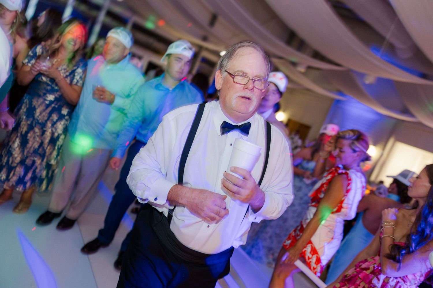 Lively wedding reception with guests dancing under ambient lighting.