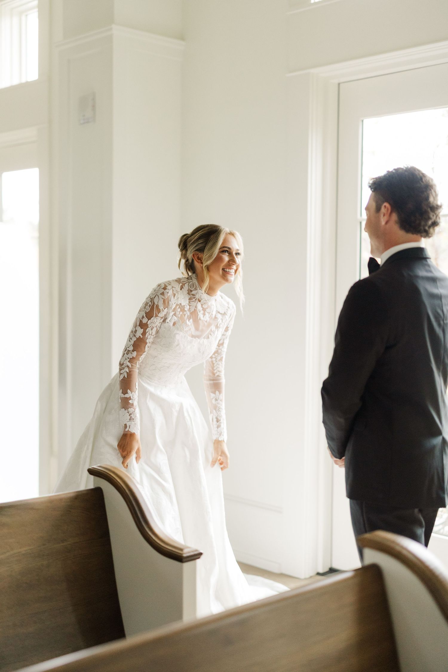 Sequence of wedding day first look moments between couple in a bright white room with wooden chairs.