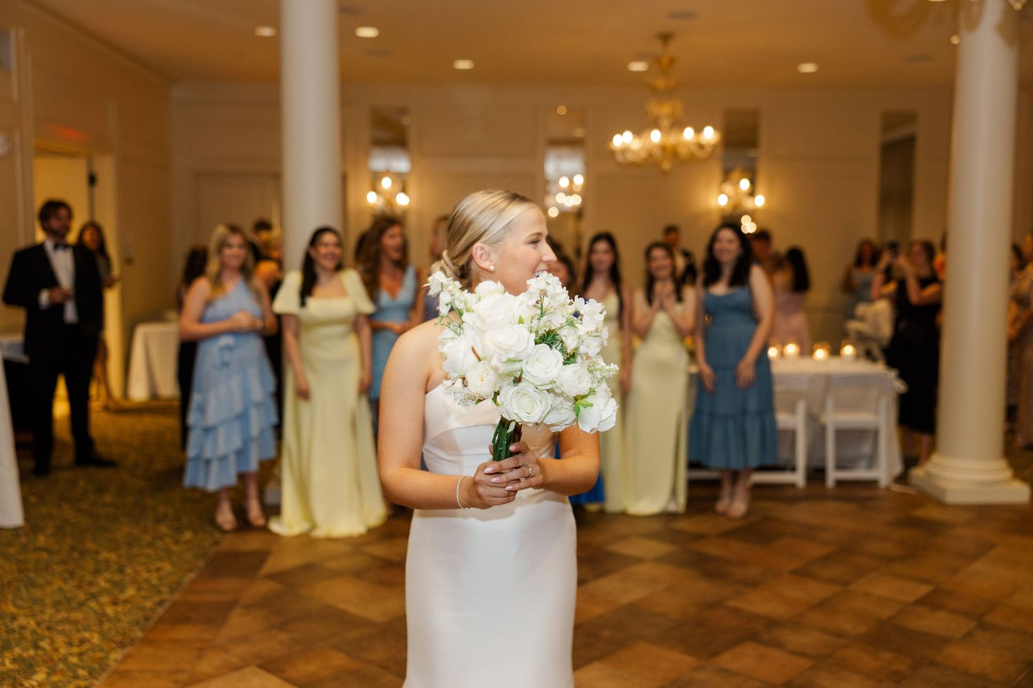 Elegant ballroom wedding reception with white columns and chandeliers.