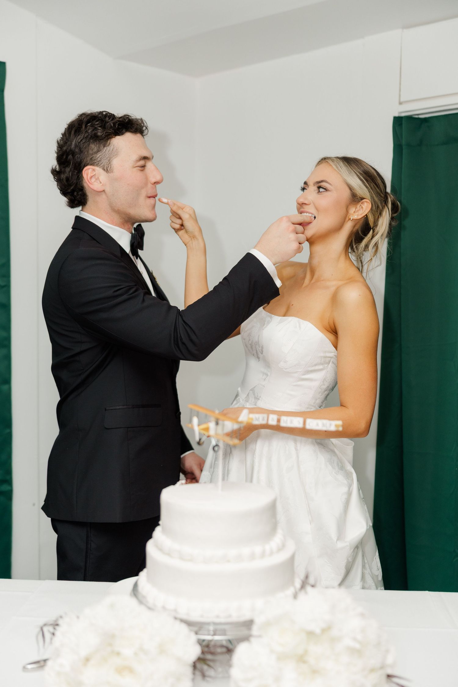 Playful cake-feeding moment between newlyweds at their wedding reception.