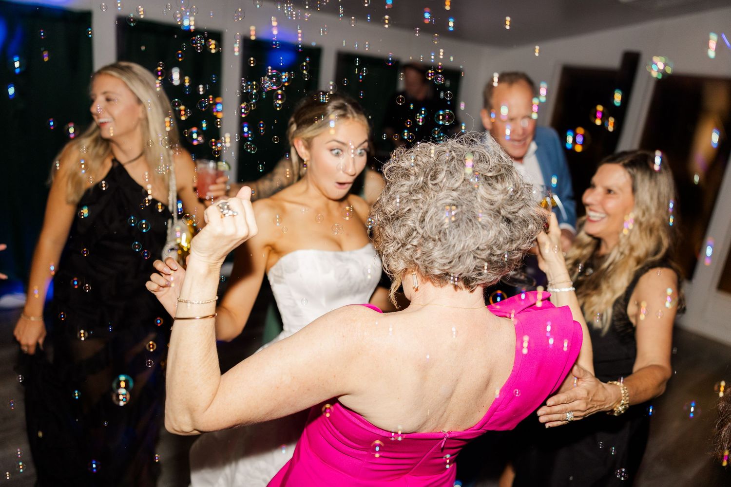 Wedding reception dance floor filled with celebrating guests under sparkling lights.