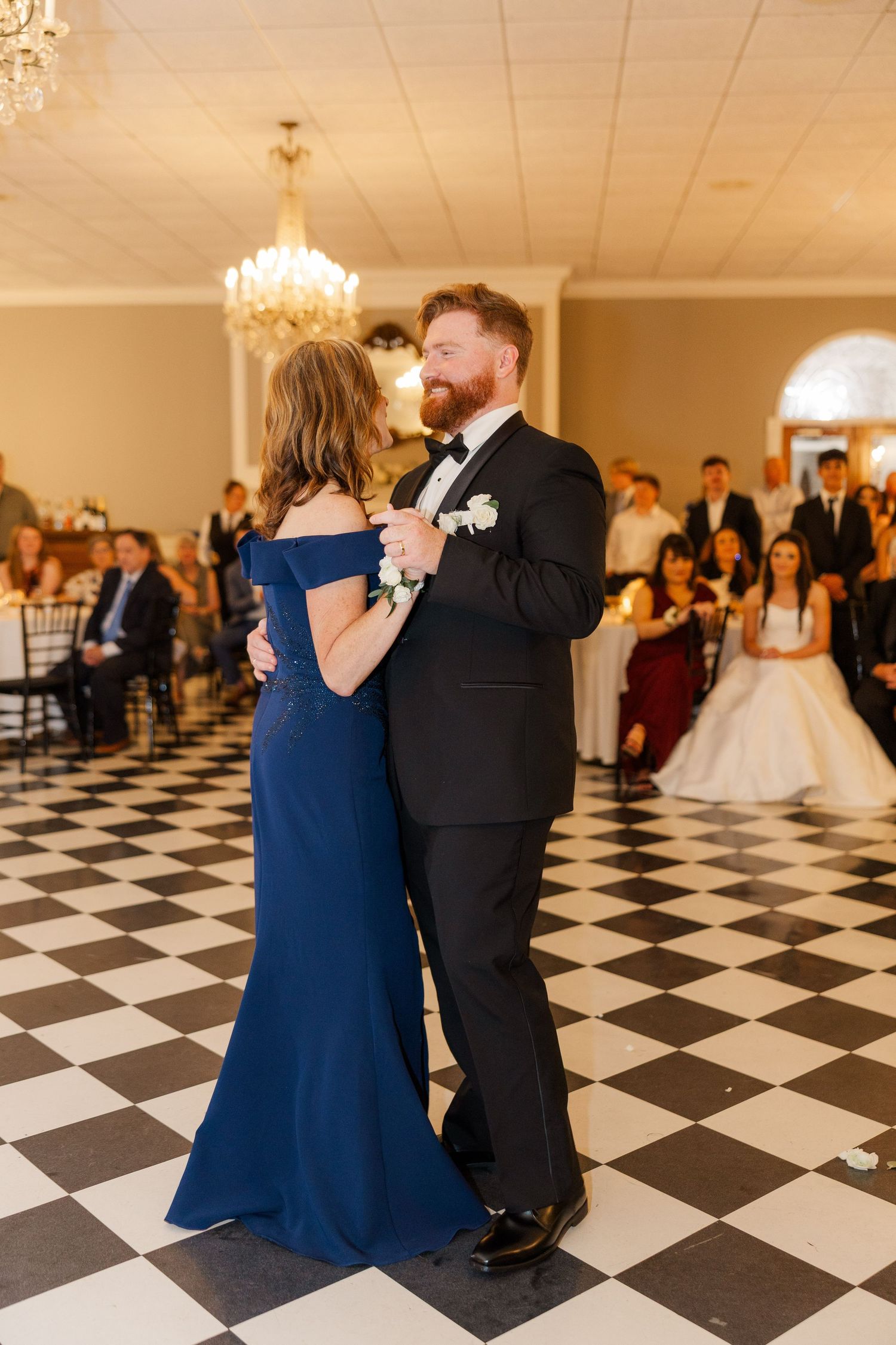 Wedding guests dance together on a striking black and white checkered ballroom floor.
