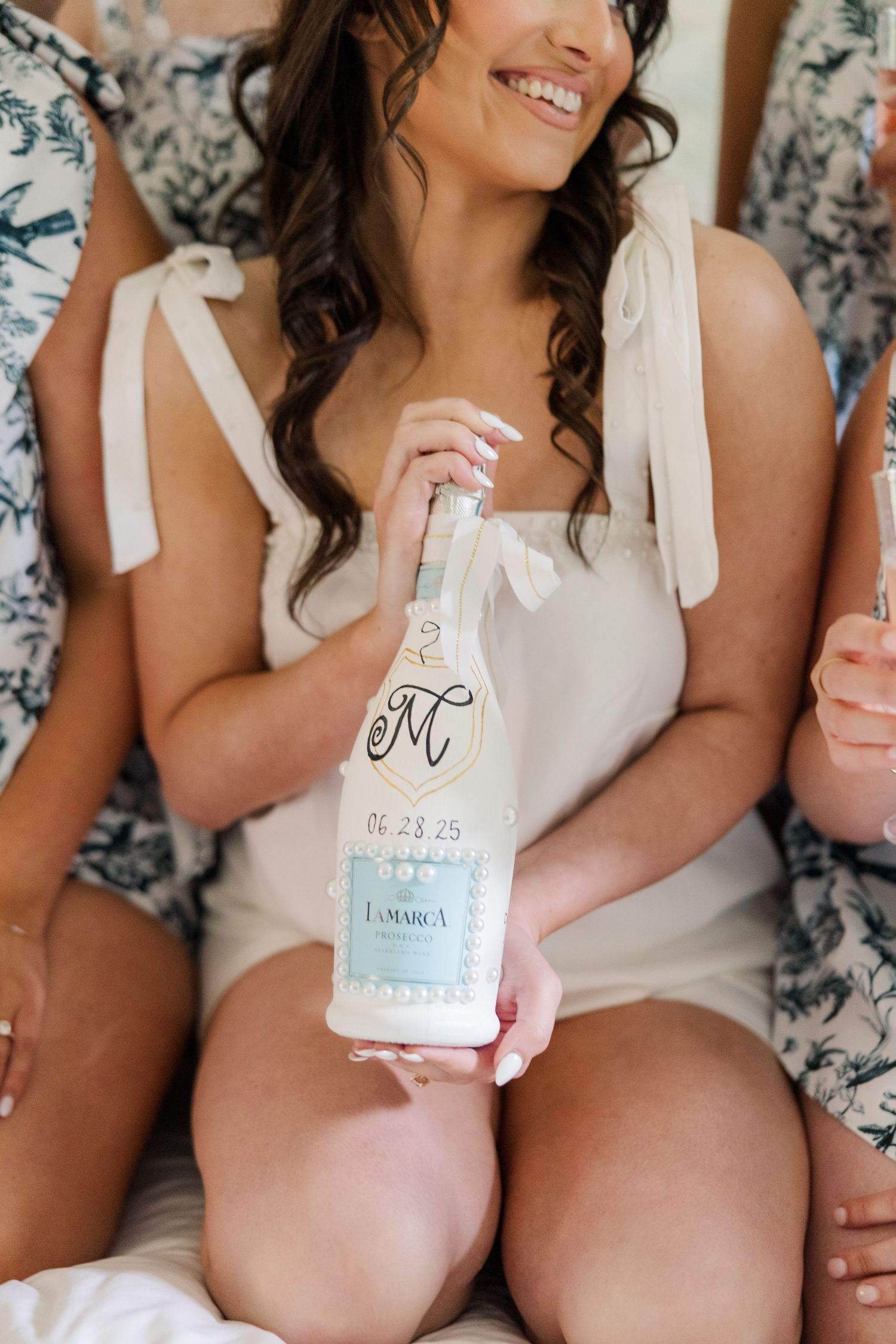 Bridesmaids in white robes holding custom wedding koozies.