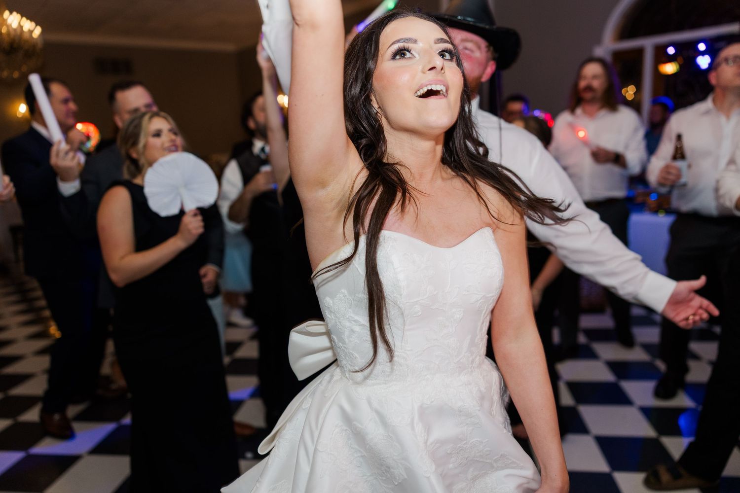 Wedding guests dancing and celebrating on a black and white checkered dance floor at an evening reception.
