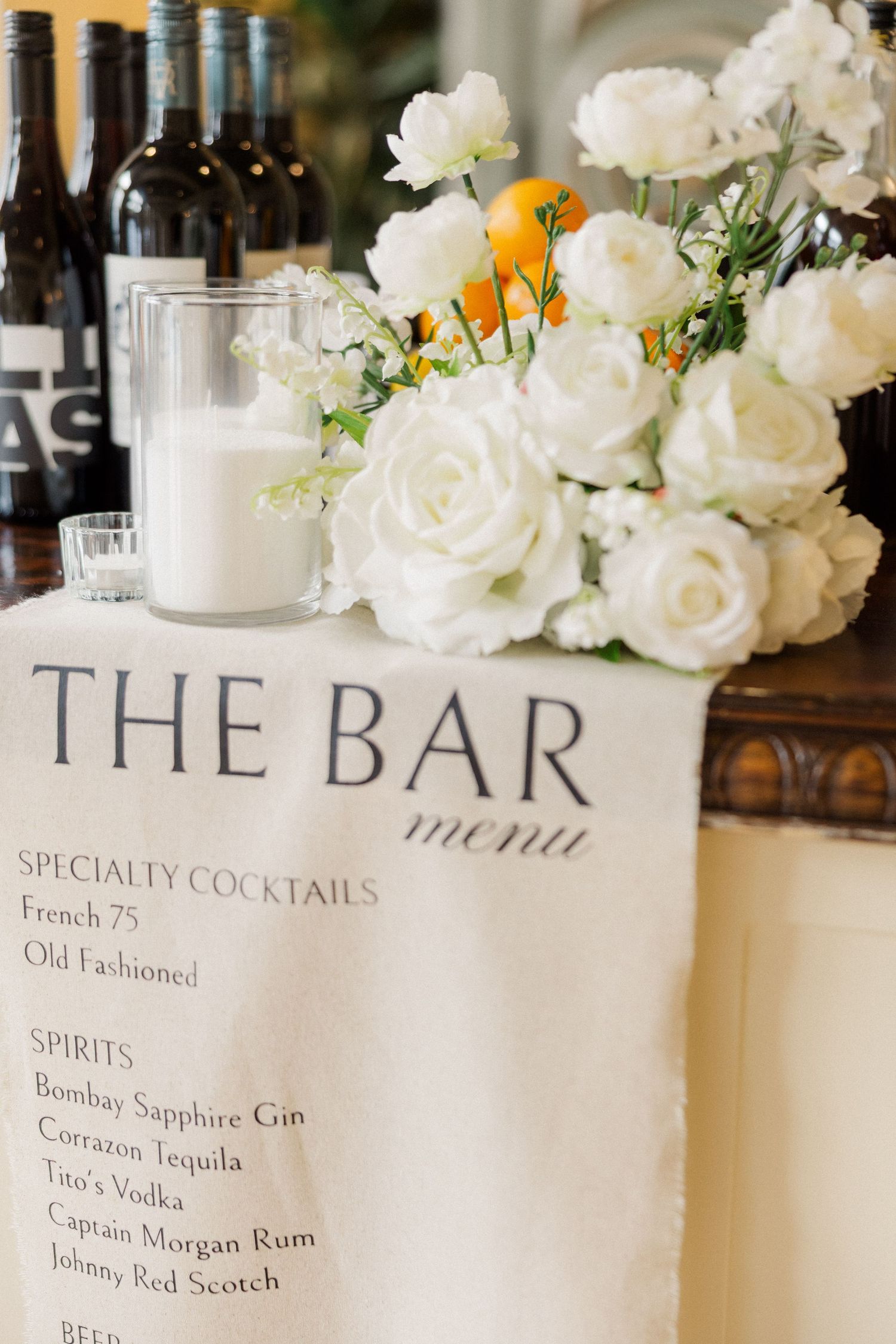 Wedding bar menu with white roses and drink selections displayed elegantly.