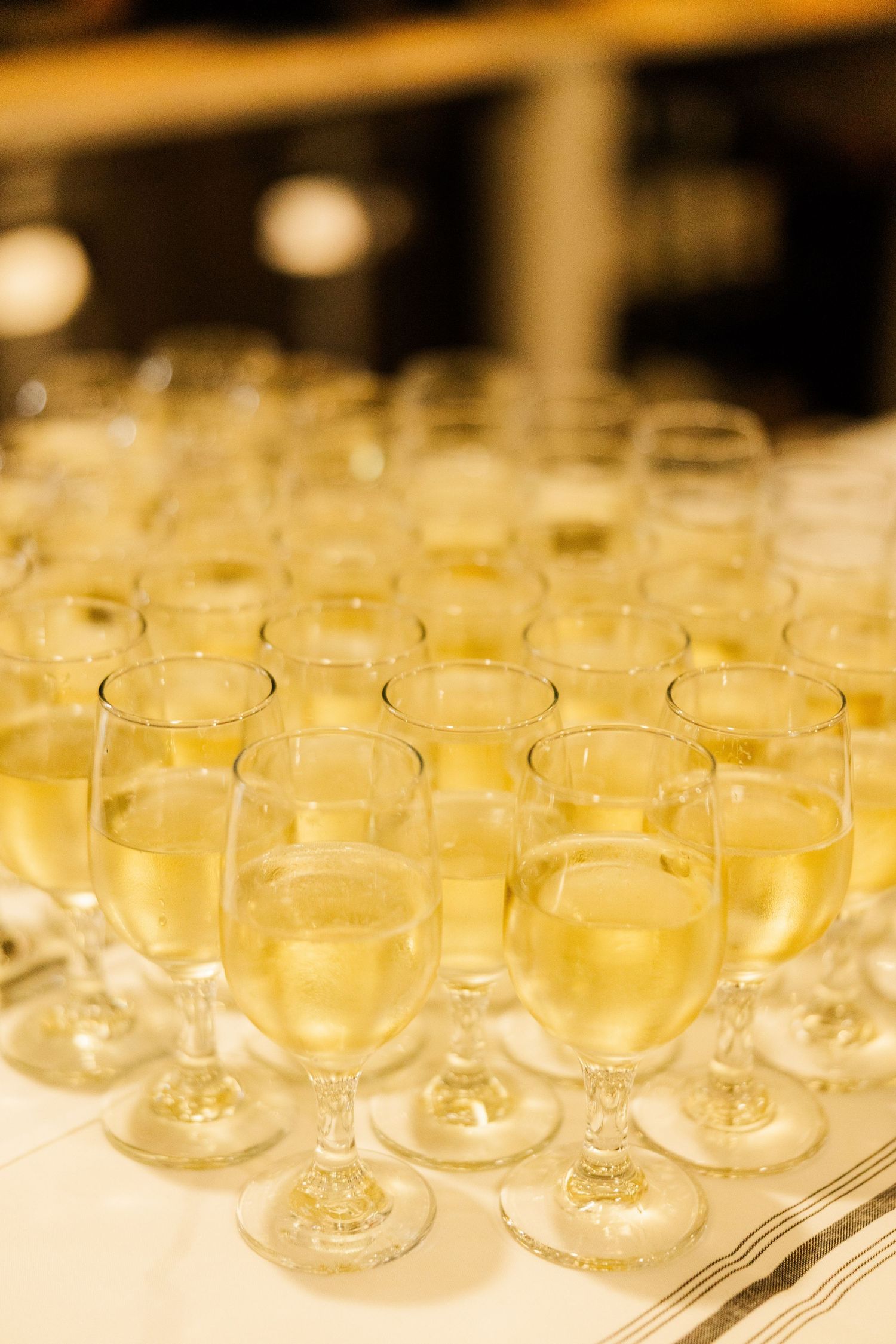 Rows of empty champagne glasses arranged on a table for a wedding reception.