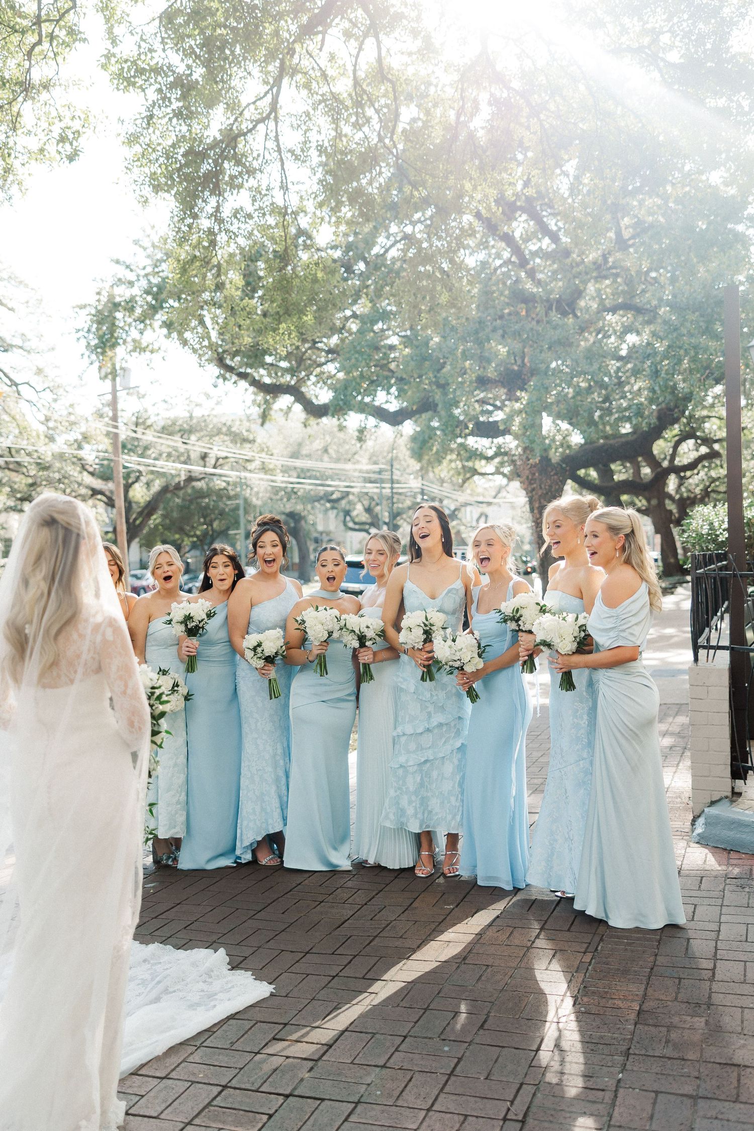 Wedding party in light blue bridesmaid dresses gathered on outdoor patio.