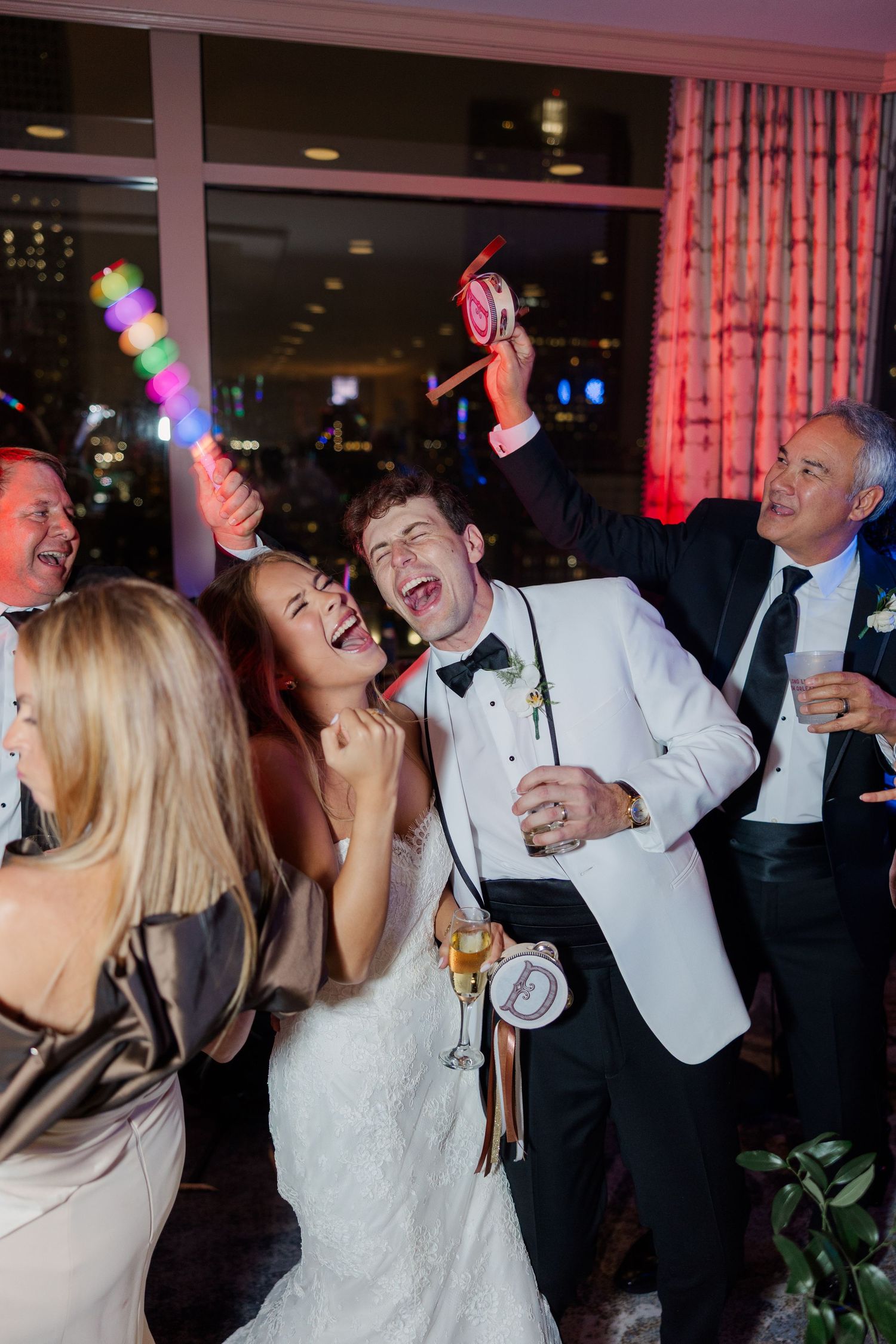 Lively dance floor scene at wedding reception with colorful lighting.