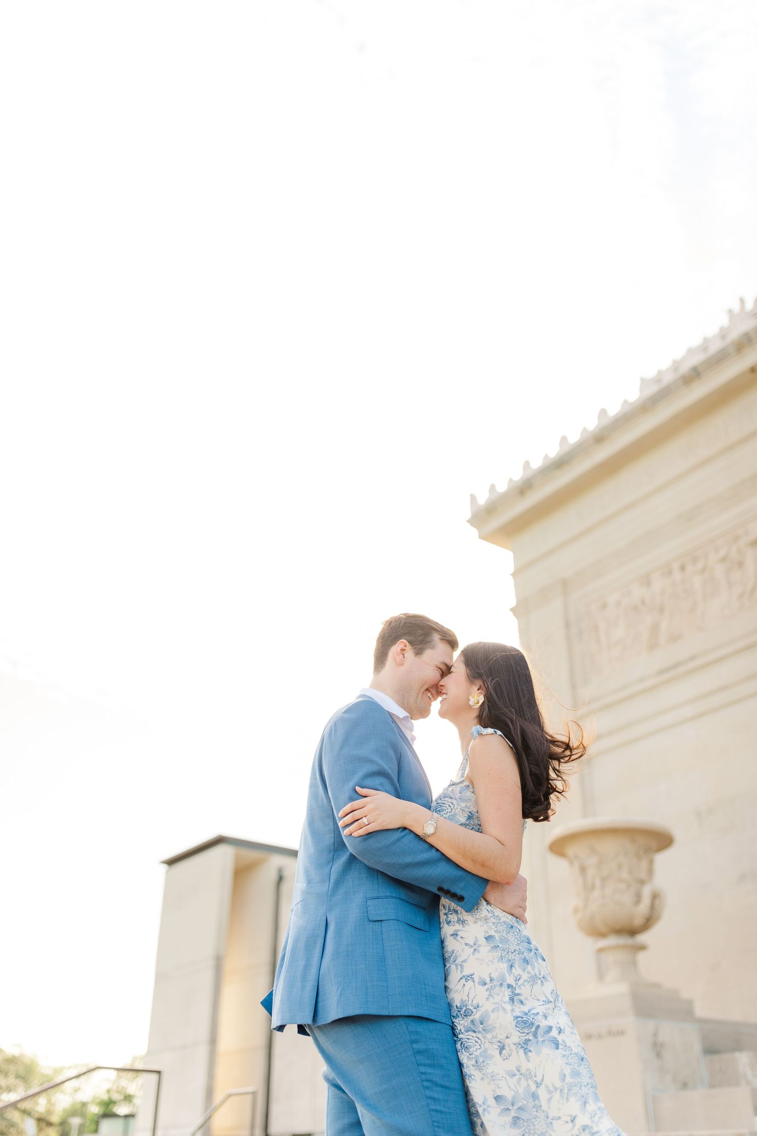 Romantic couple embracing against elegant architectural backdrop in evening light.
