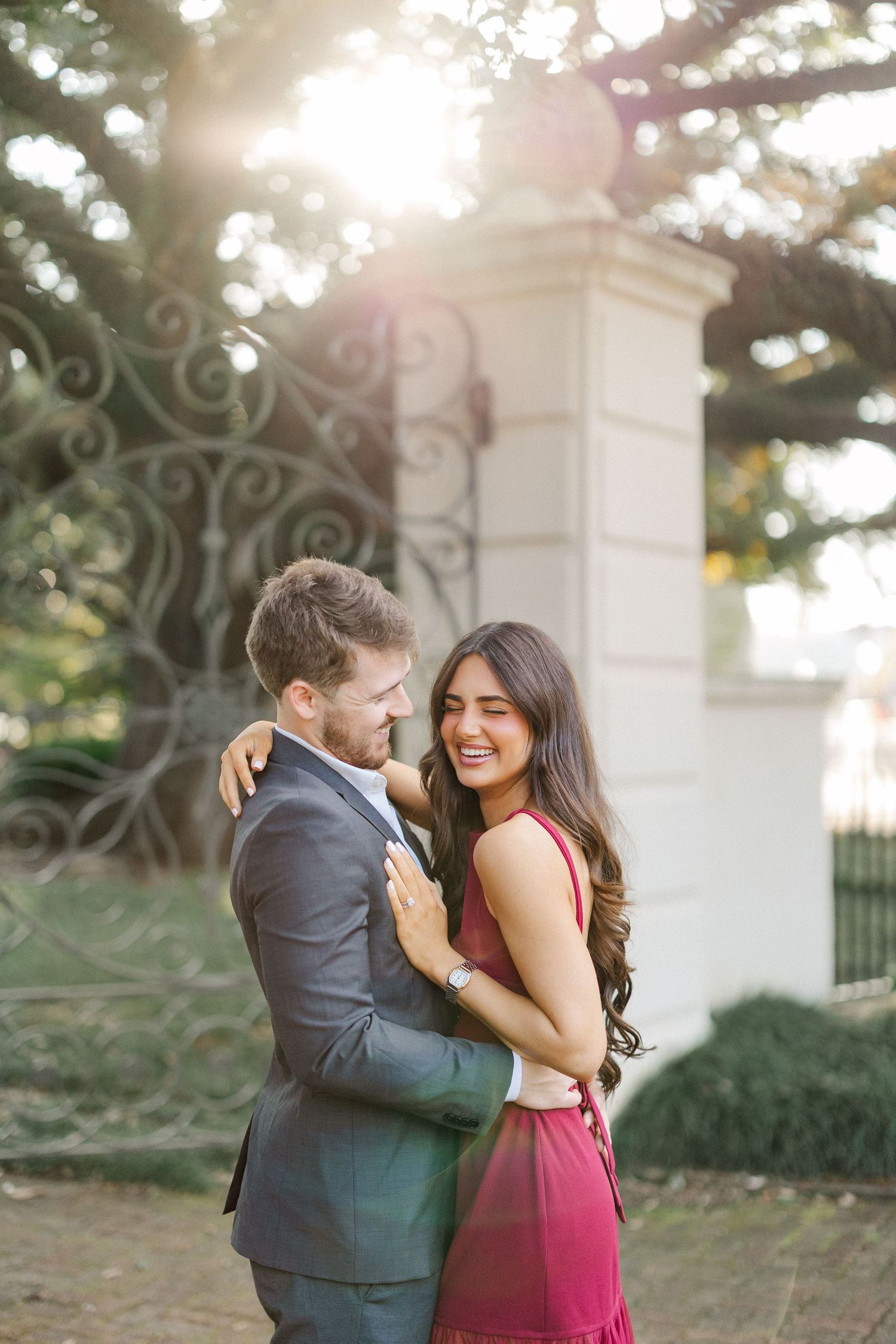 A romantic couple embraces in front of a white stone pillar during a sunset photoshoot.