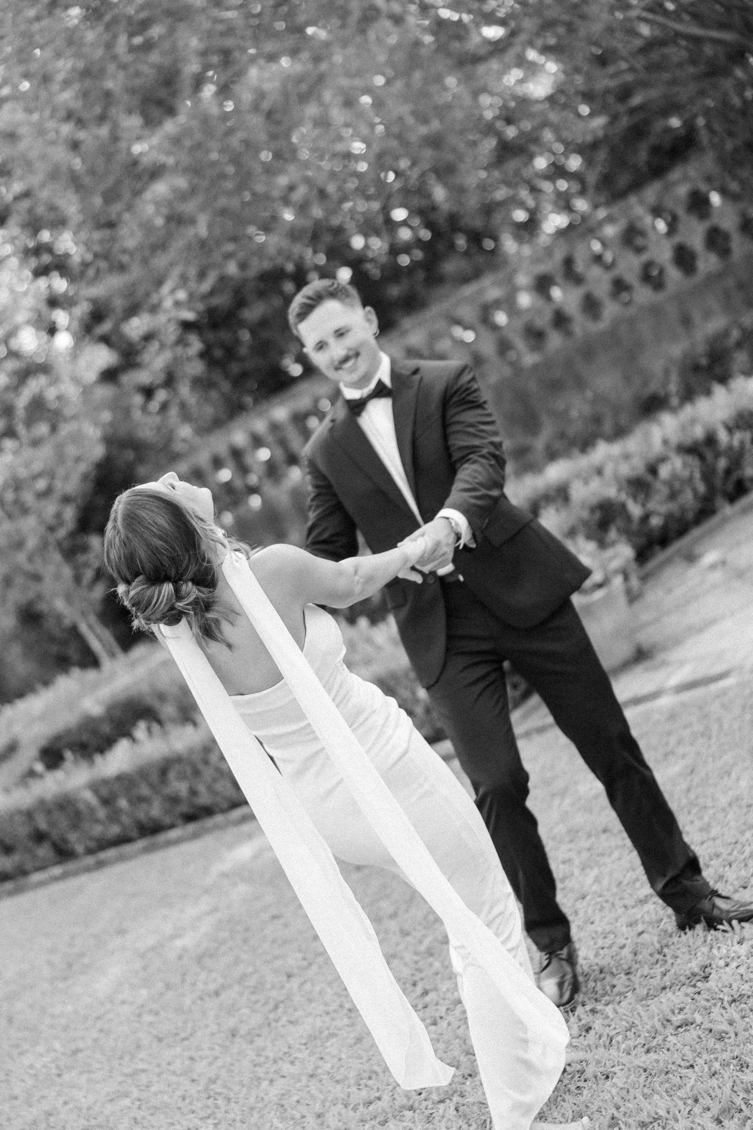 Black and white wedding photo sequence shows playful moments between couple on grassy lawn.