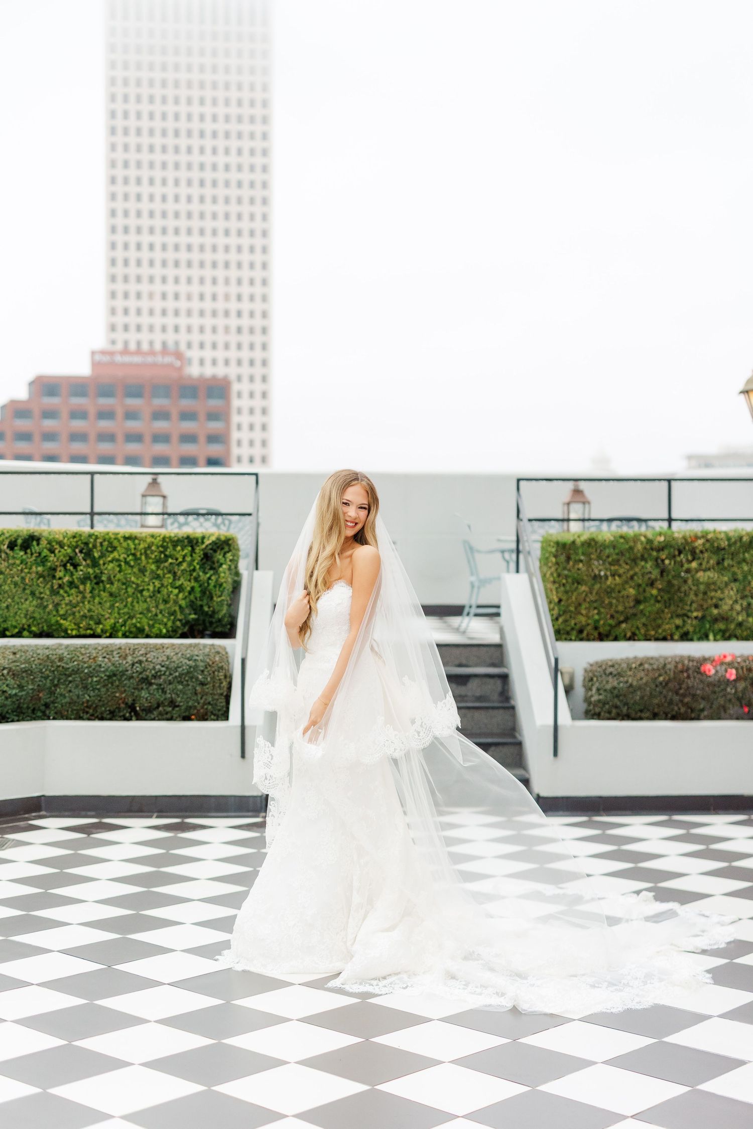Flowing white wedding dress twirling on black and white checkered floor with city backdrop.