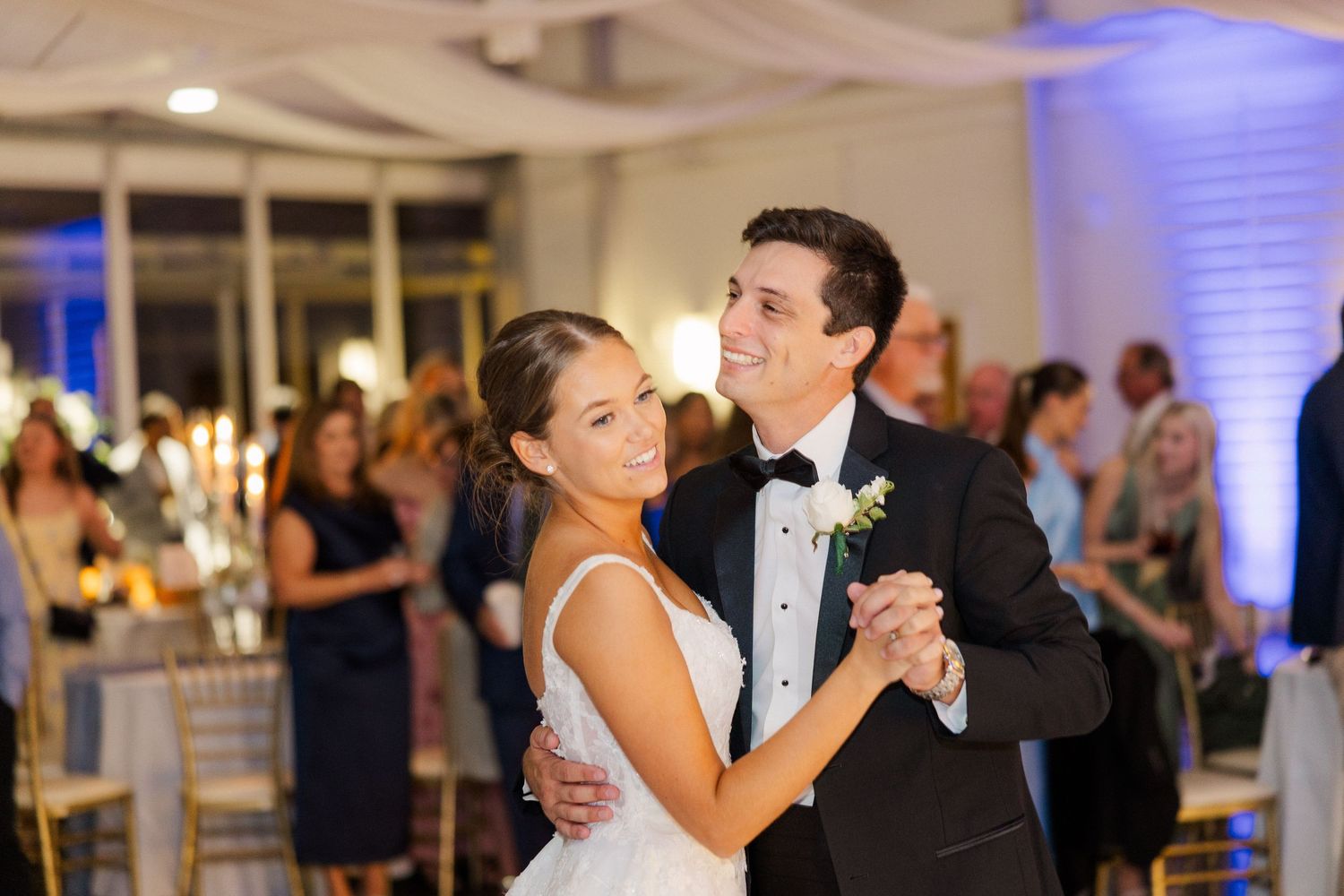 Couple dancing at wedding reception with blue uplighting and white draping.