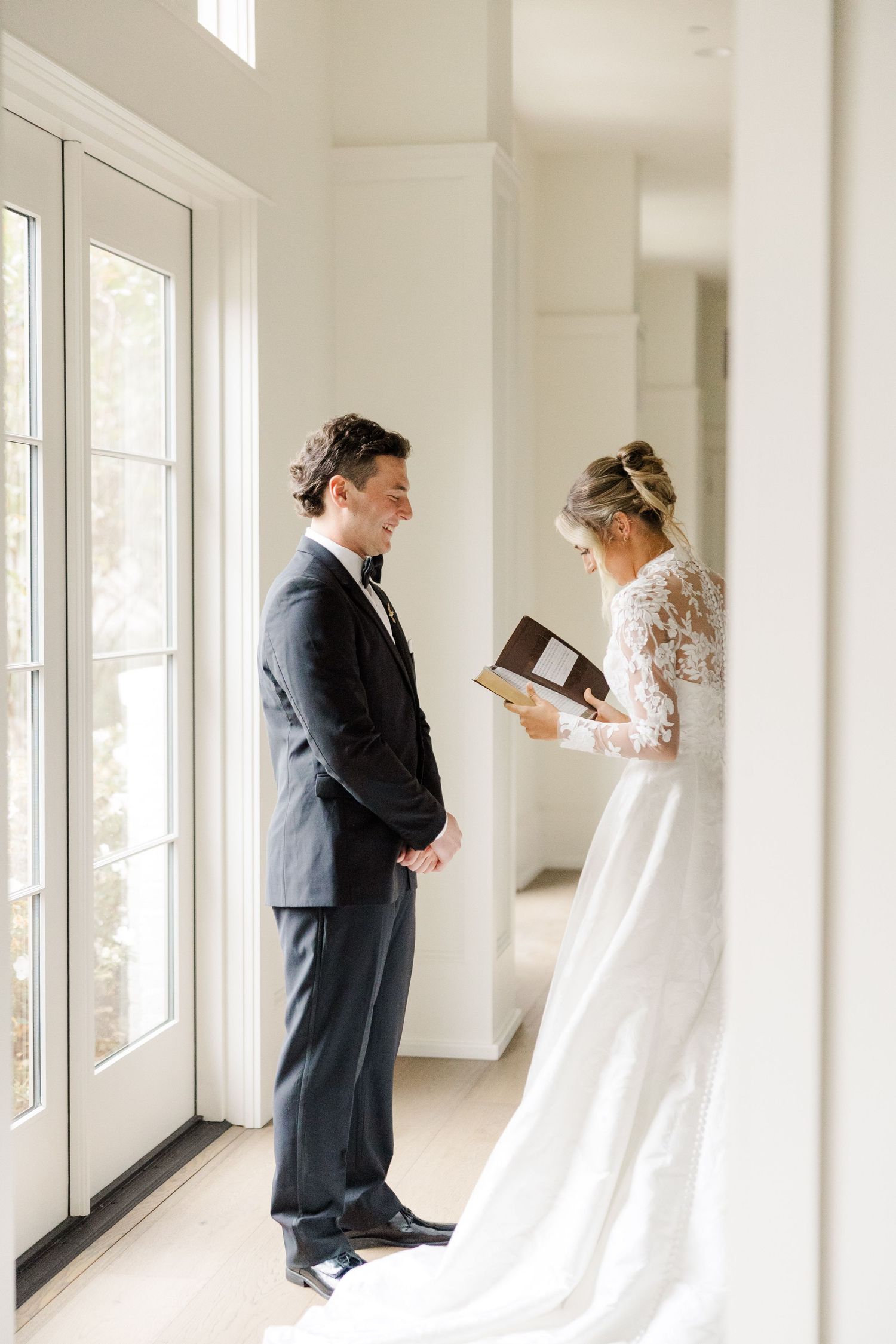 Wedding couple reading private letters in a bright sunlit hallway before ceremony.