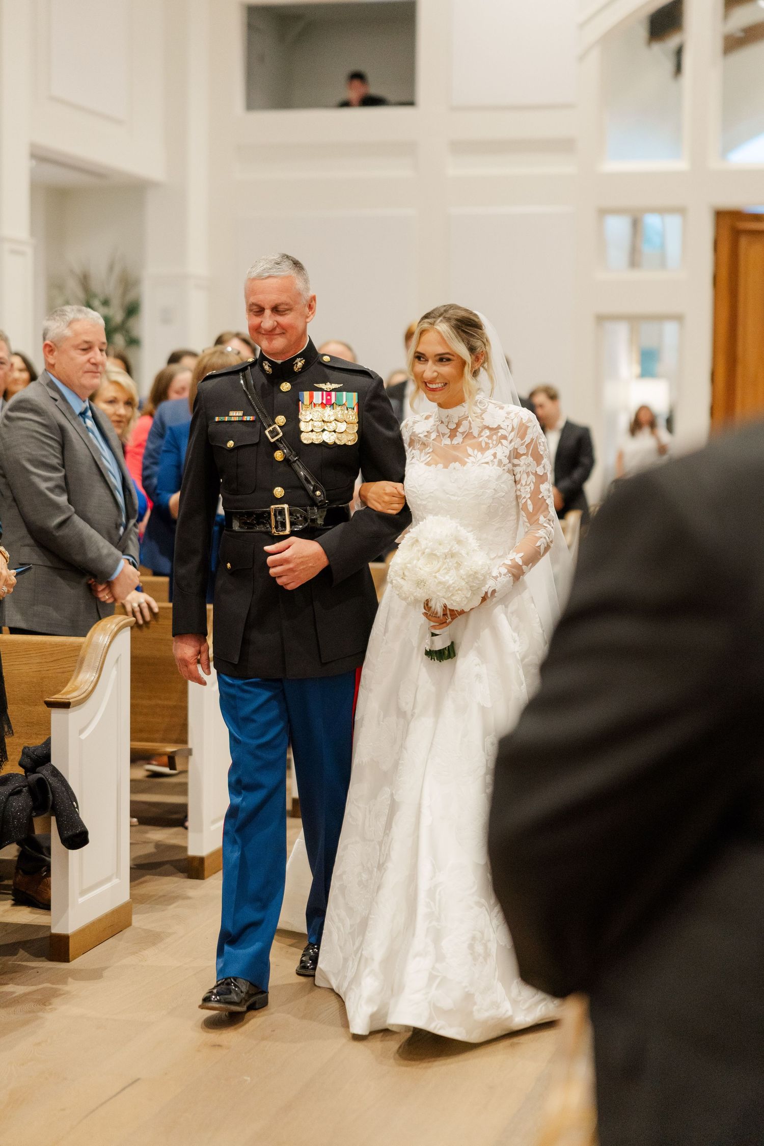 Wedding ceremony in a bright church with military service member and bride walking down the aisle.