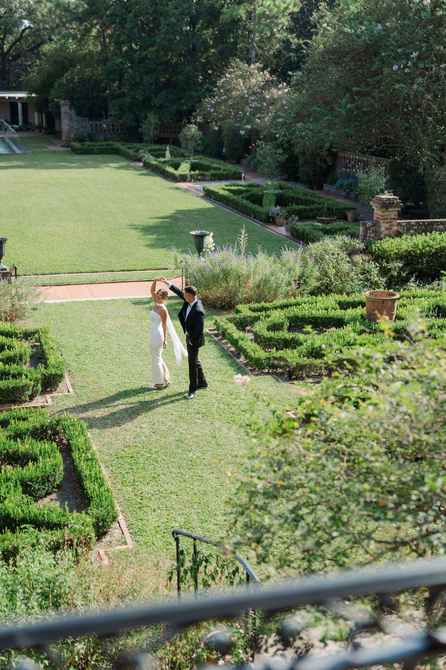 A scenic garden landscape with manicured hedges and green lawns stretches out under a sunny sky.