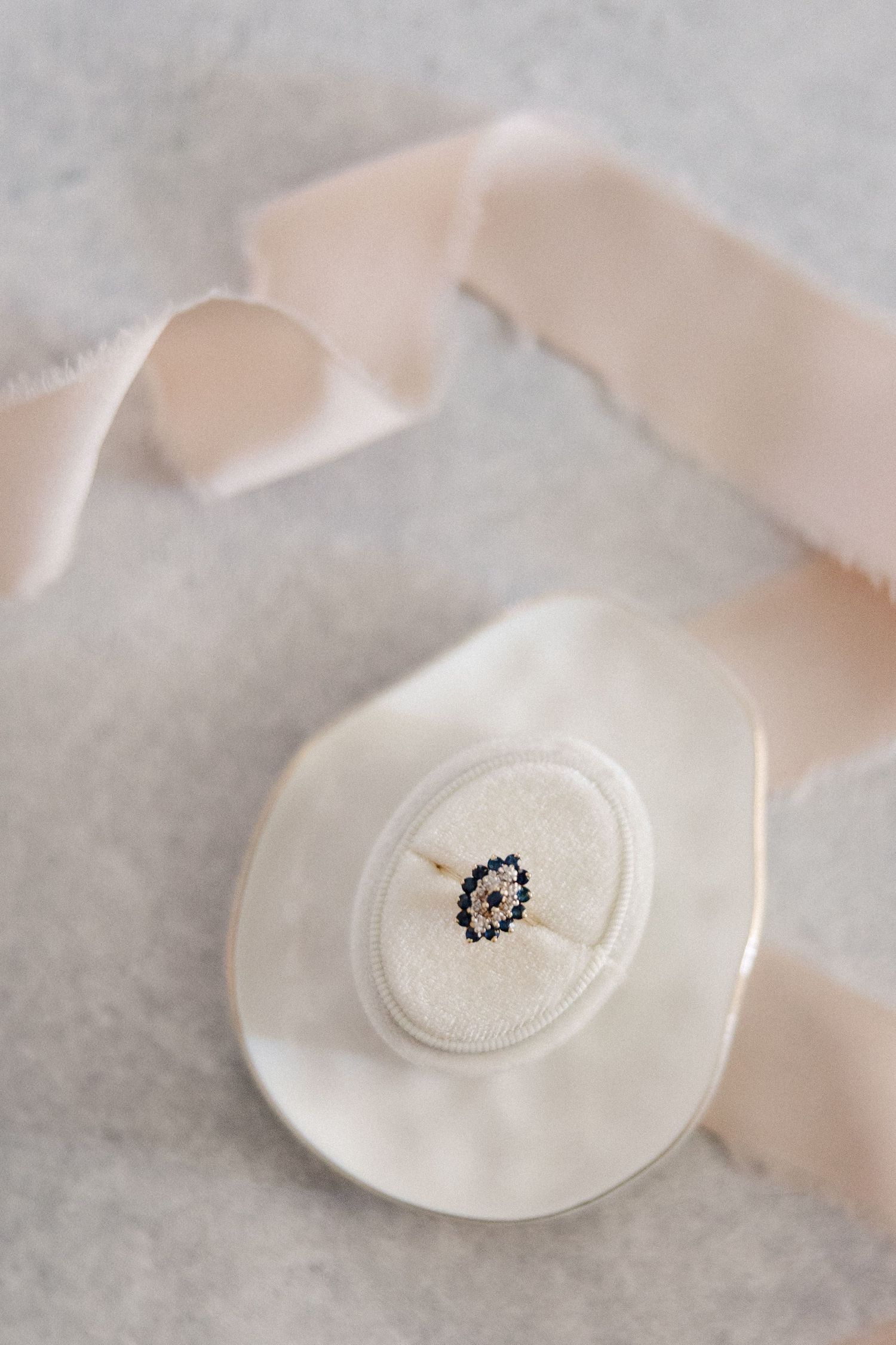A delicate white button with a small decorative detail on a soft pink ribbon.