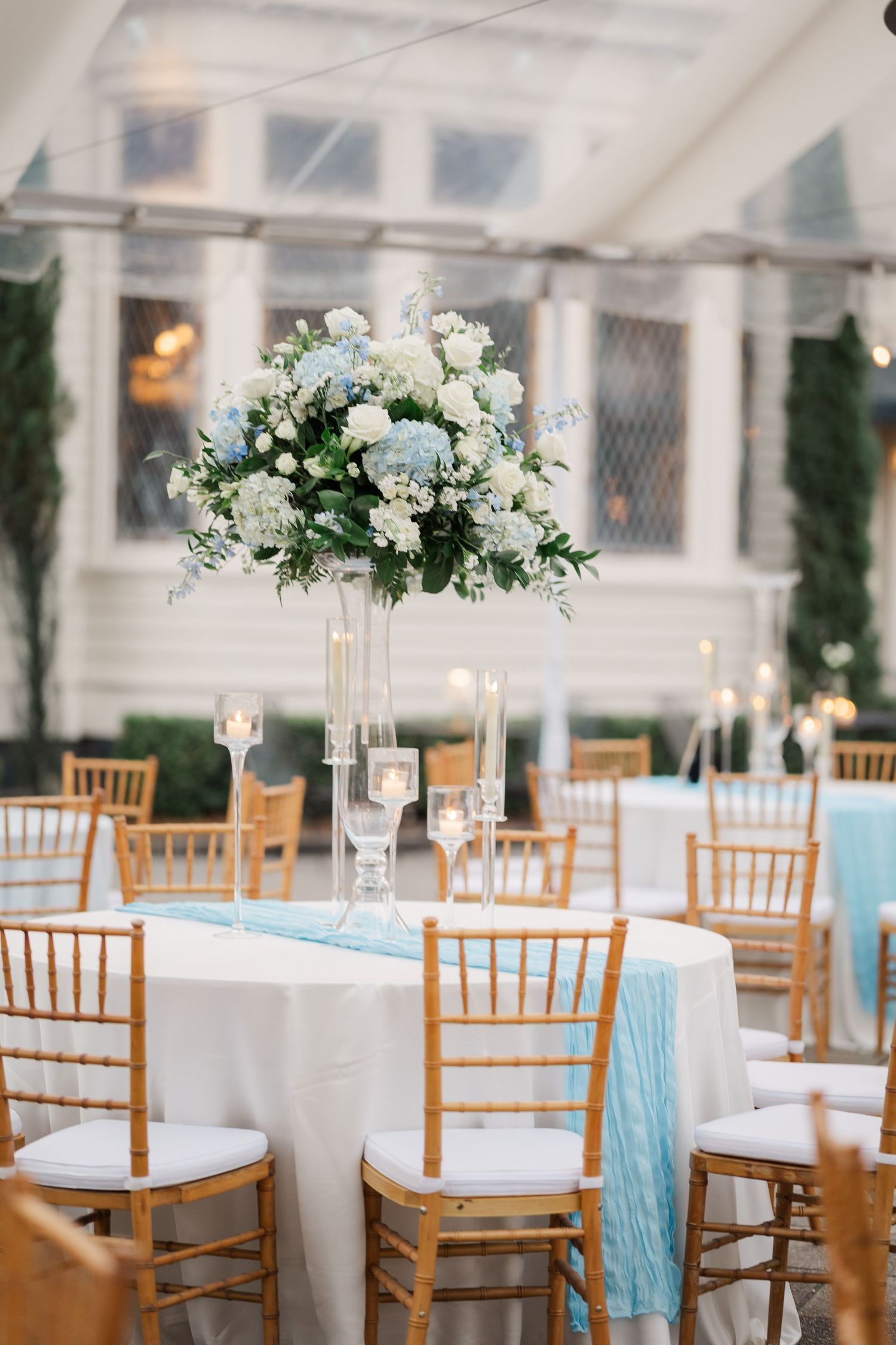 Elegant wedding reception tables with white floral centerpieces and light blue table runners.