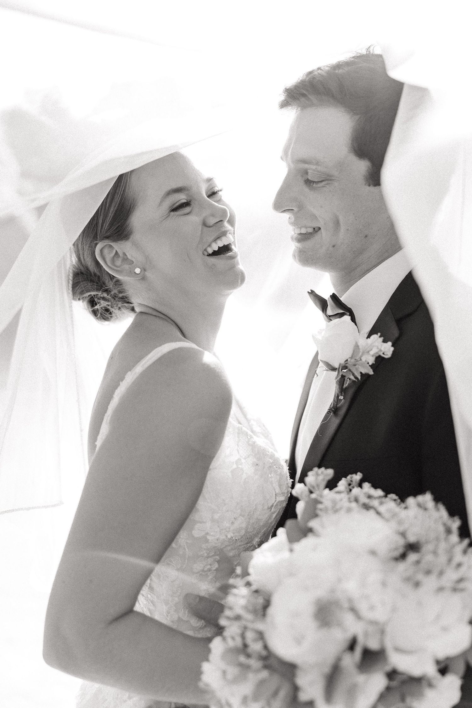 Black and white wedding photos capturing candid laughter and joy between newlyweds.