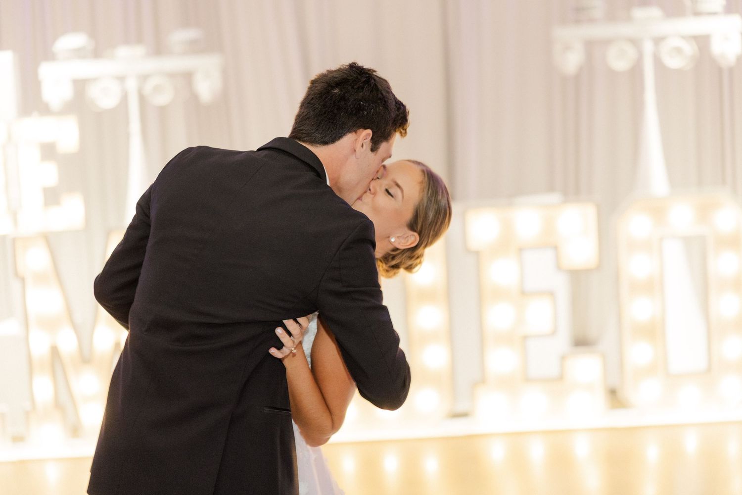 Romantic first dance at wedding reception with dramatic dip pose.