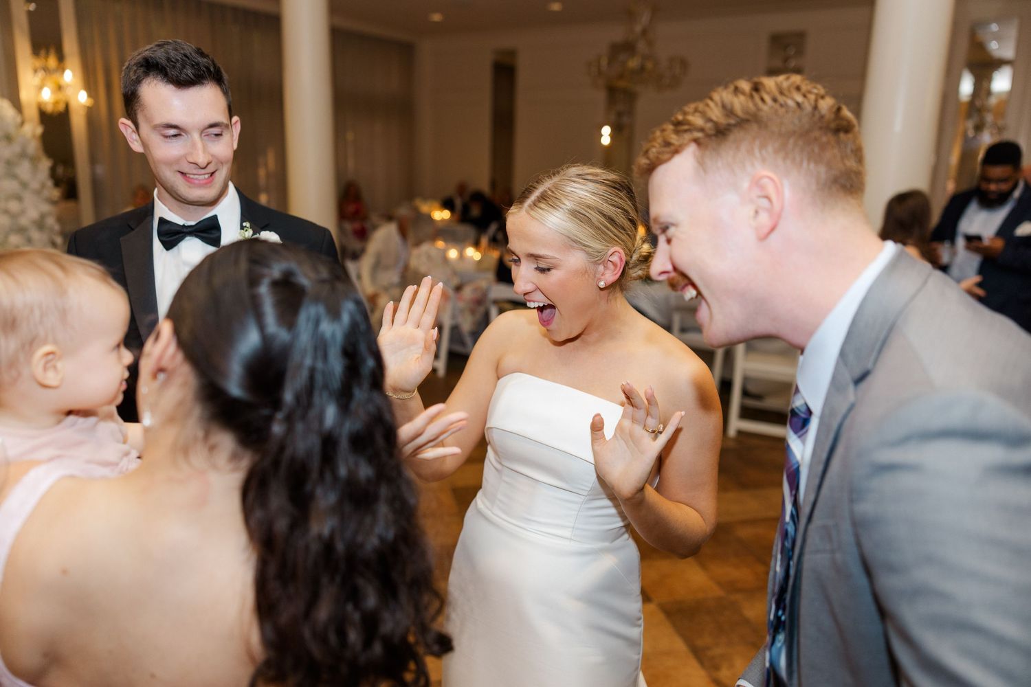 Wedding guests dancing and celebrating at an elegant indoor reception.