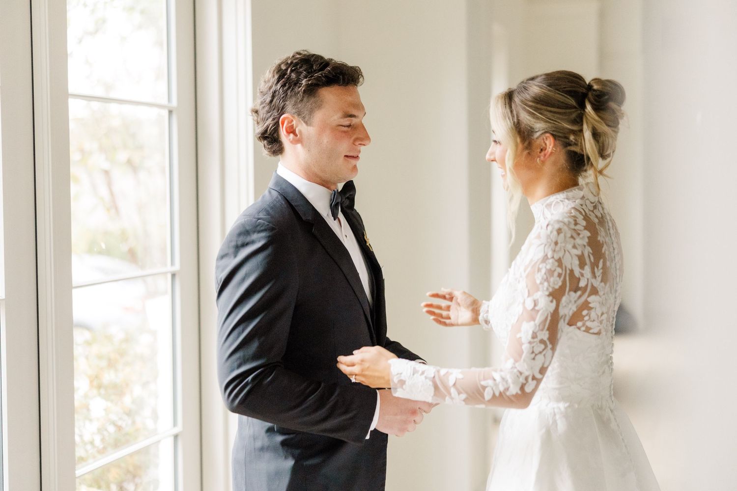 Emotional wedding day first look between a couple in a bright sunlit room.