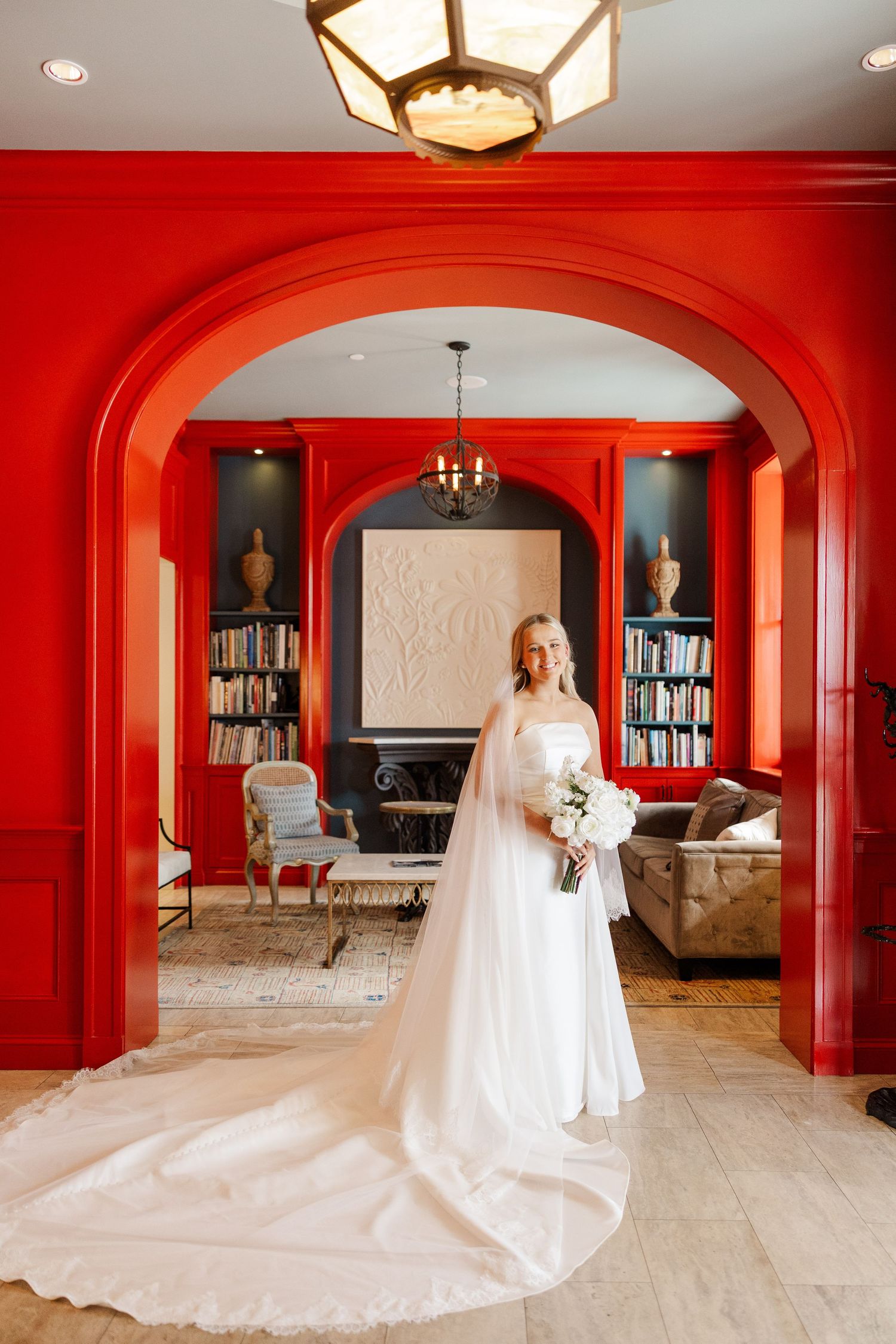 Bridal portraits in a luxurious red-walled room with dramatic lighting and architectural details.
