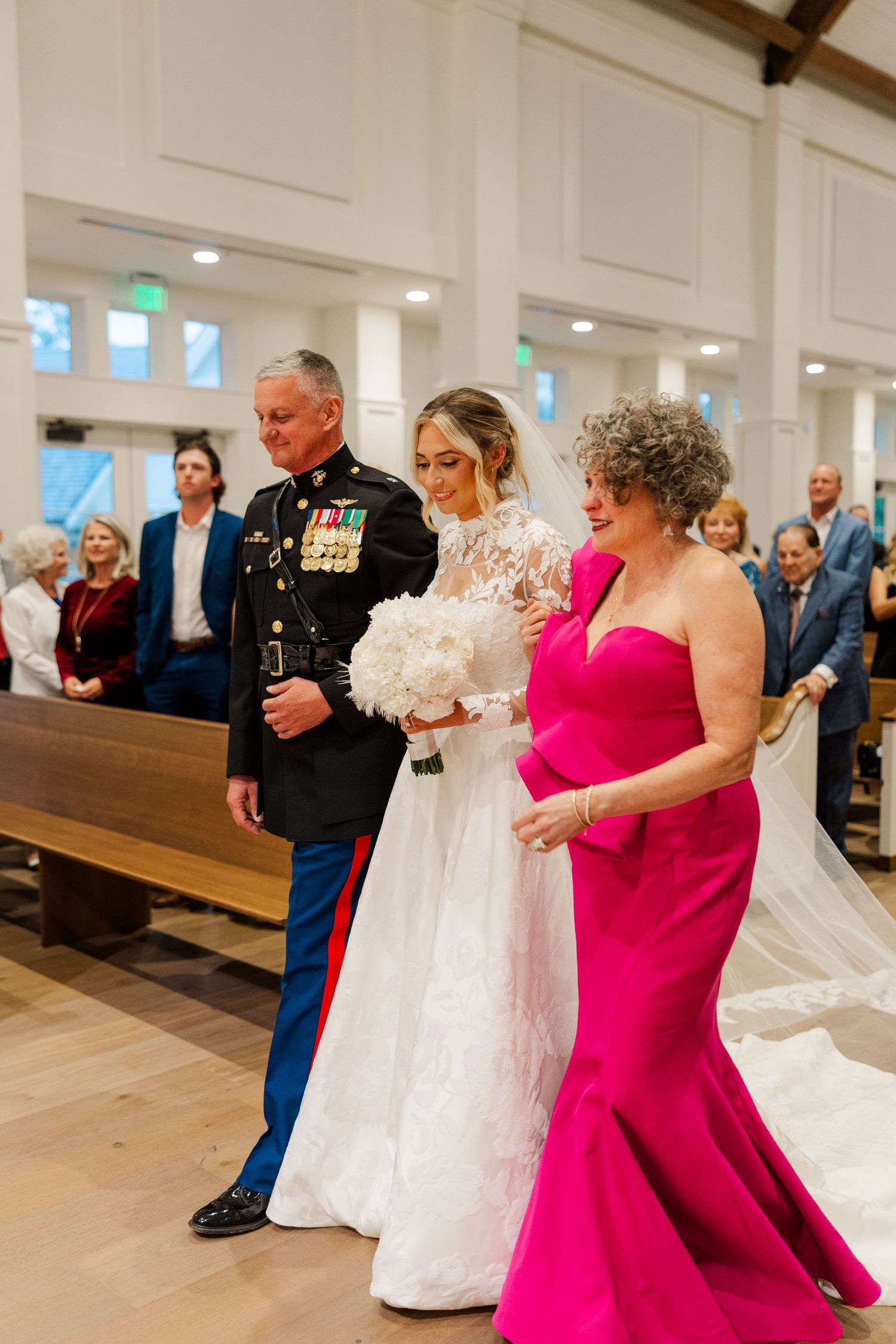 Wedding party with bridesmaids in bright pink dresses celebrating in a modern church setting.