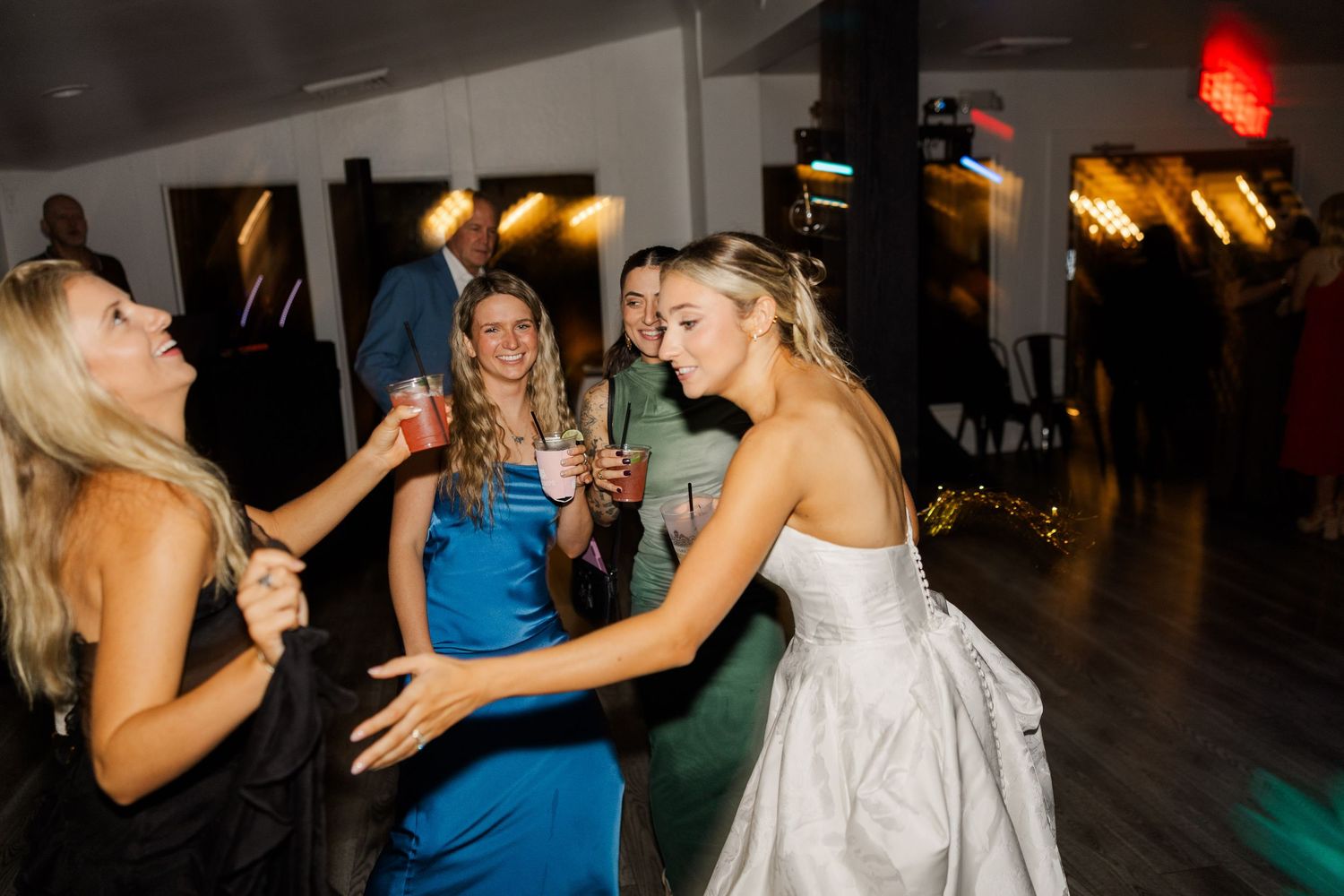 Wedding reception dance floor filled with guests celebrating under ambient lighting.