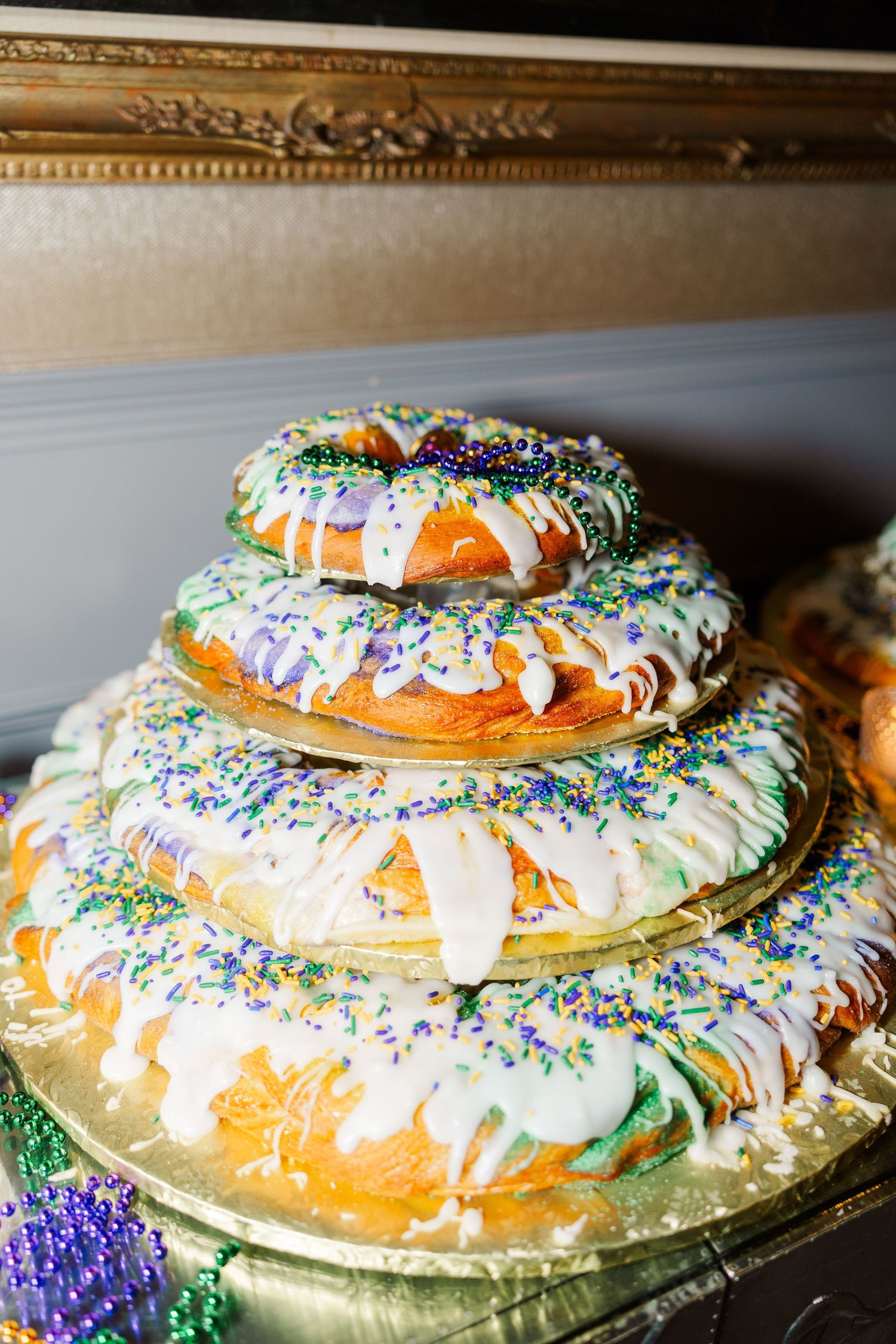 Festive king cake decorated with colorful sprinkles and icing displayed on an ornate gold surface.