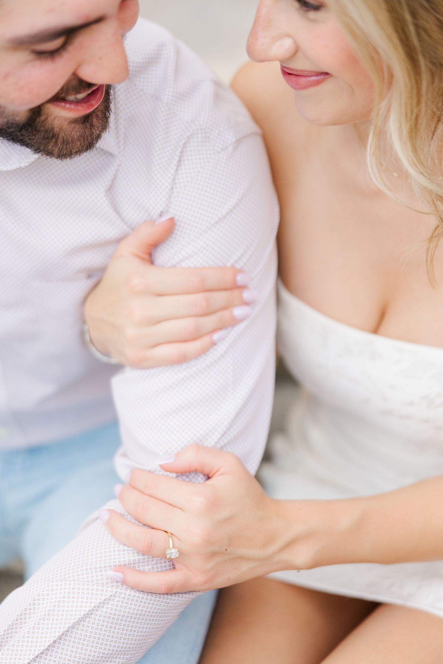 A close-up shot of a couple in white clothing sharing an intimate moment and holding hands.