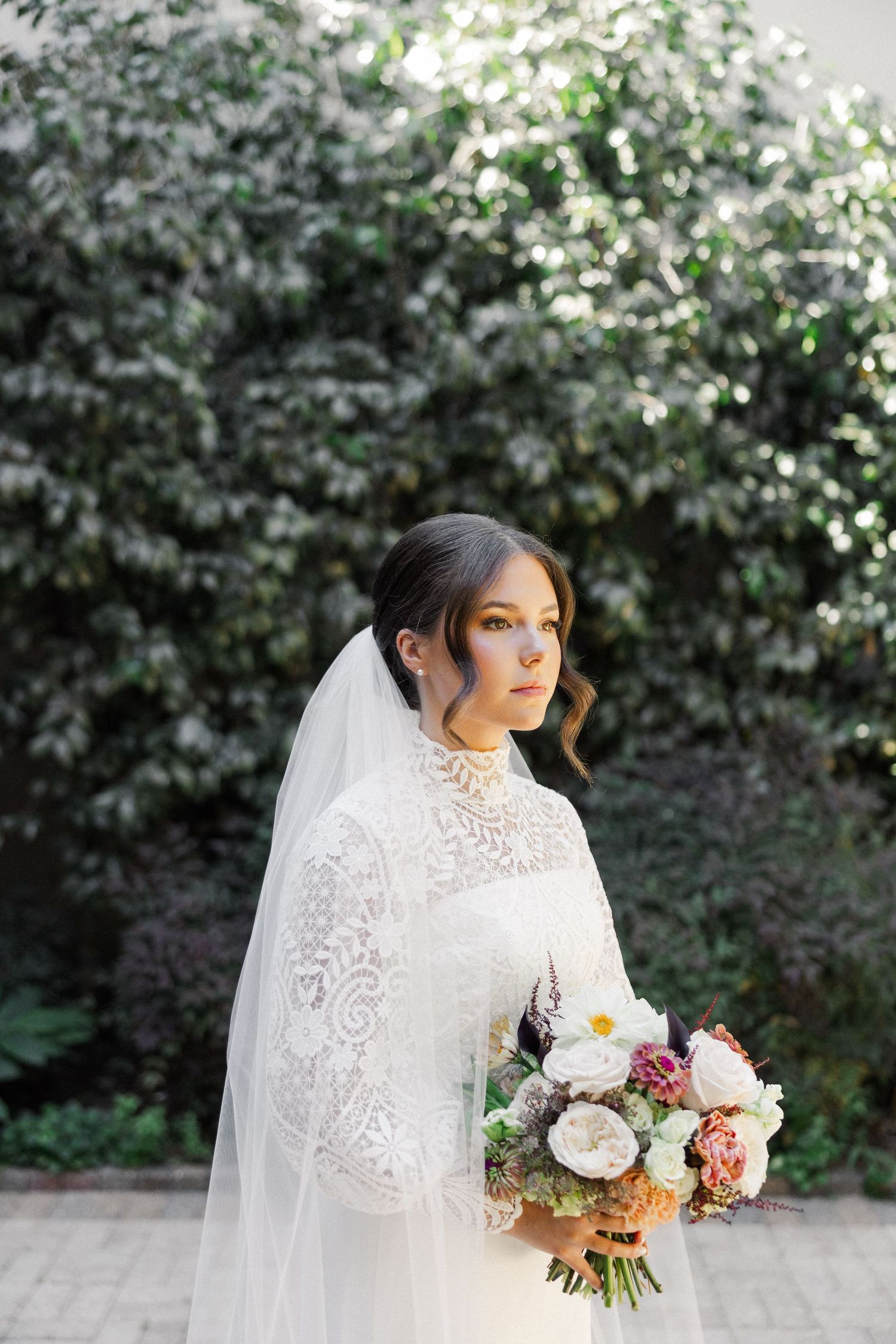 Outdoor bridal portraits against lush greenery showcasing a classic white lace wedding dress and floral bouquet.