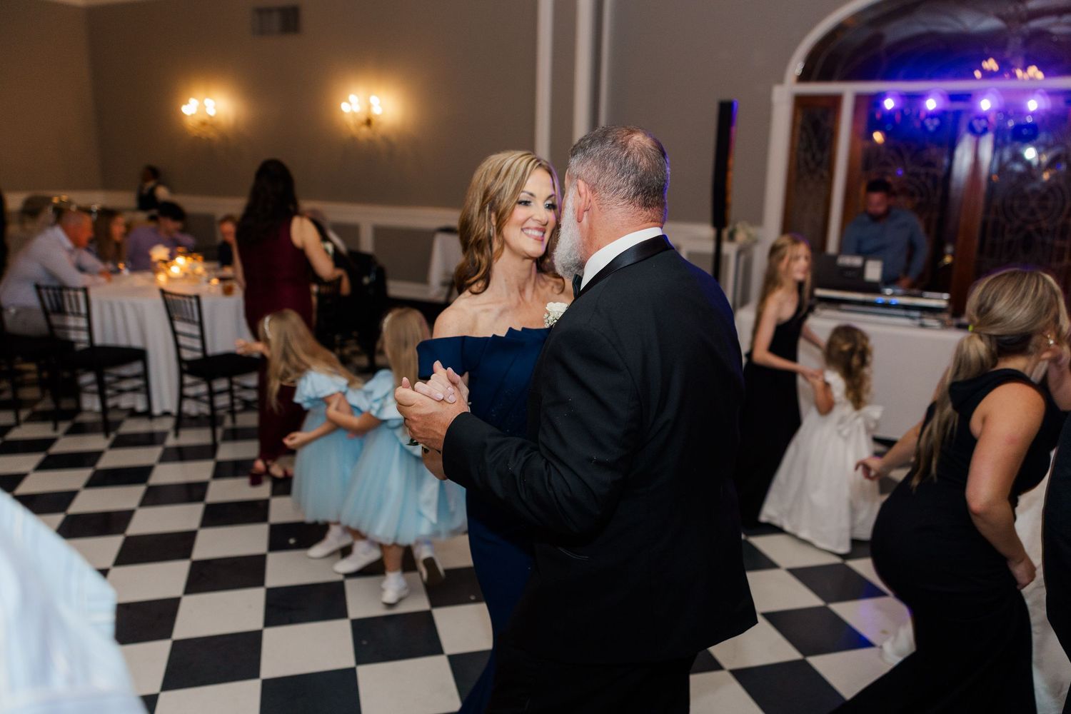 Wedding guests dancing and celebrating on black and white checkered dance floor.