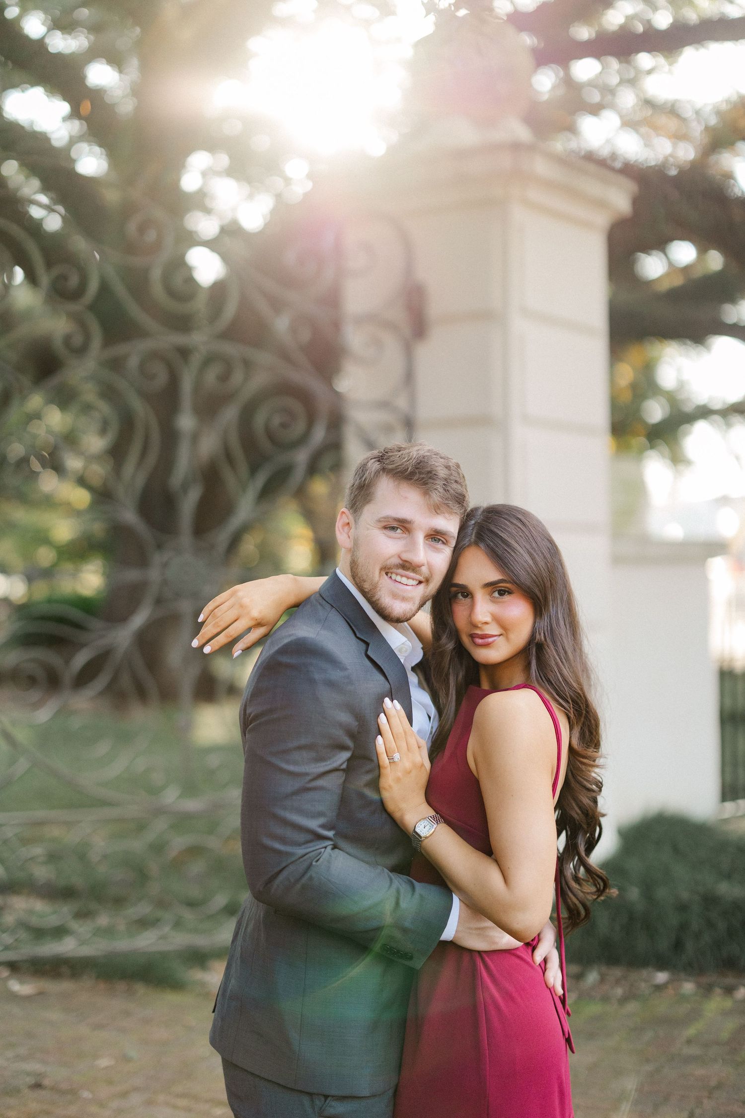 A romantic couple poses together in a garden setting with beautiful natural lighting.