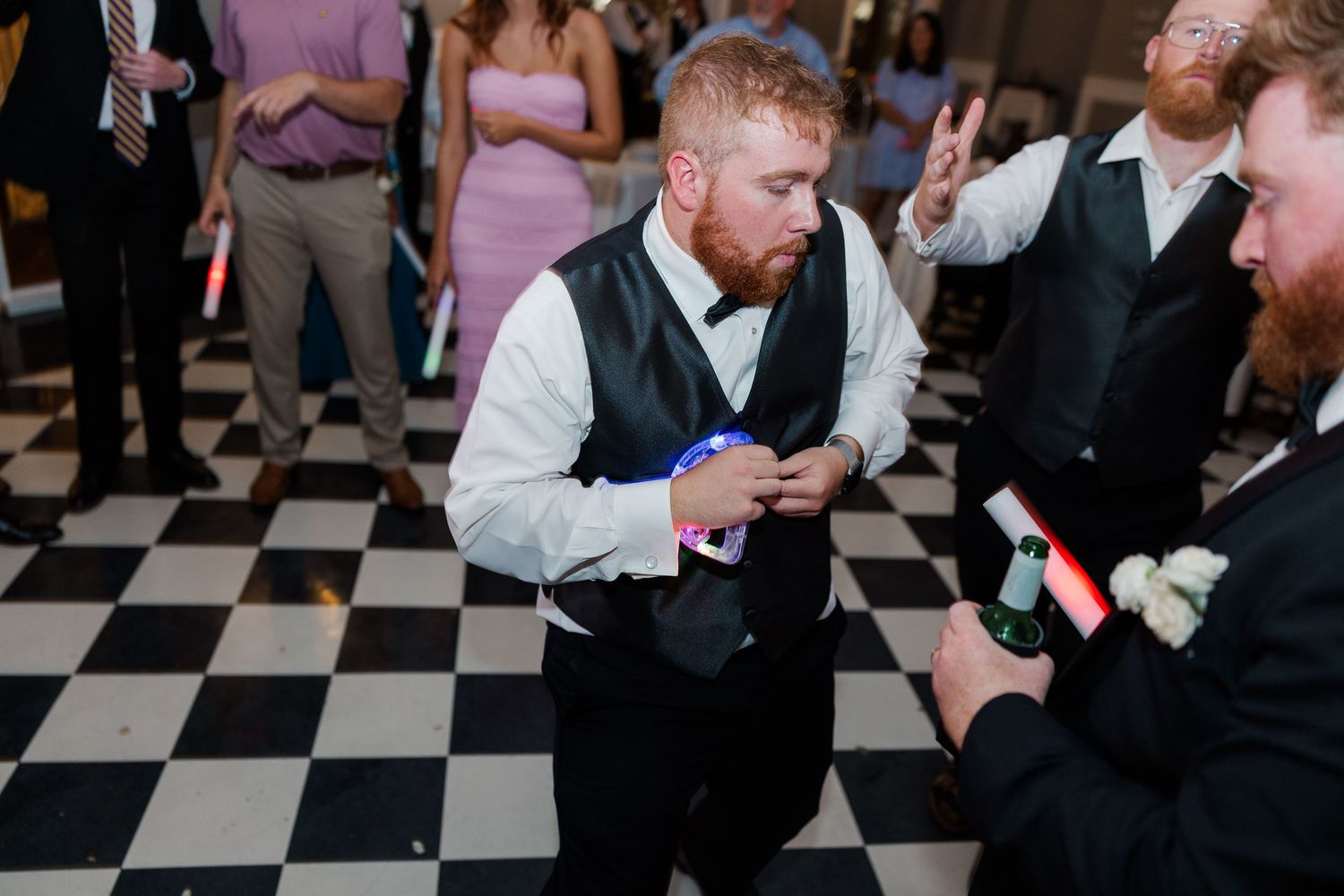 Wedding guests enjoying themselves on a black and white checkered dance floor during the reception.