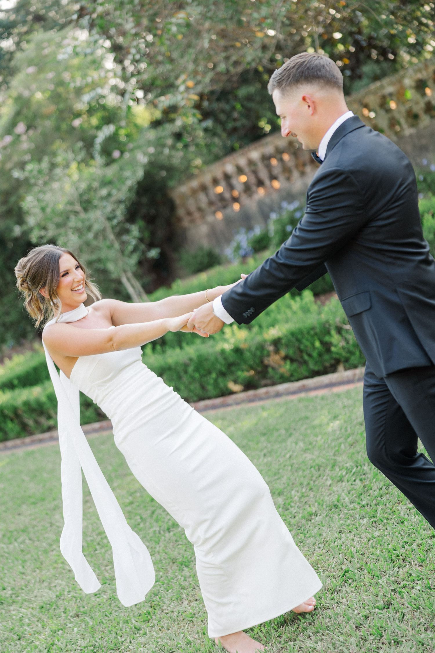 Playful sequence of dance moves on a grassy lawn with bride in white dress and groom in black suit.