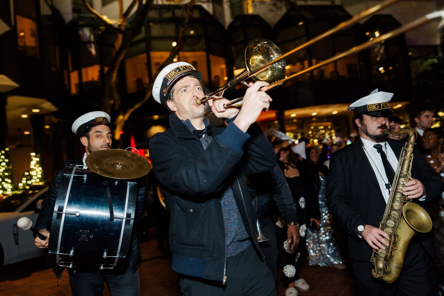 Jazz musicians perform on stage with brass instruments and formal attire during a nighttime concert.