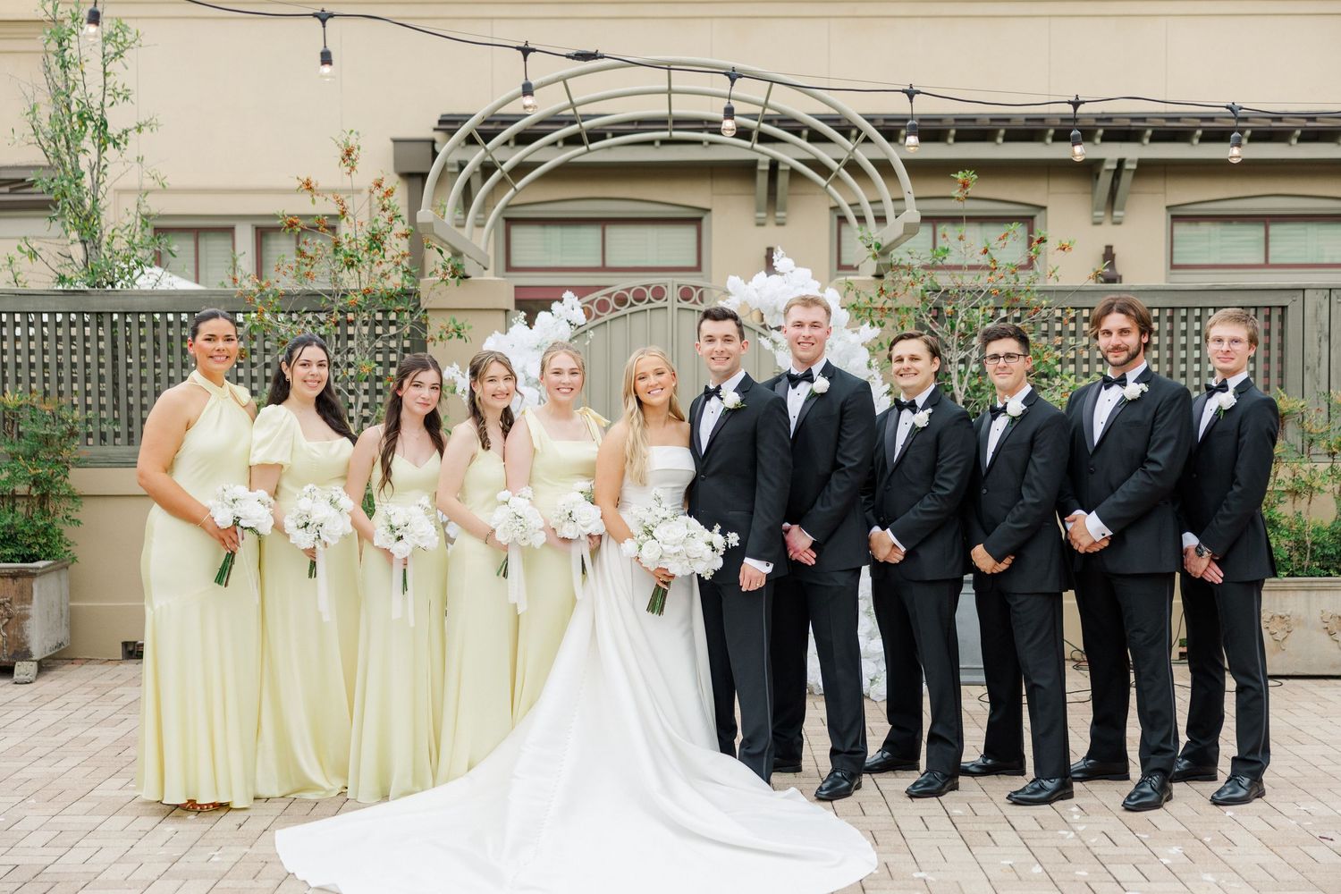 Wedding party members arranged in formal poses on stone steps of an elegant venue.