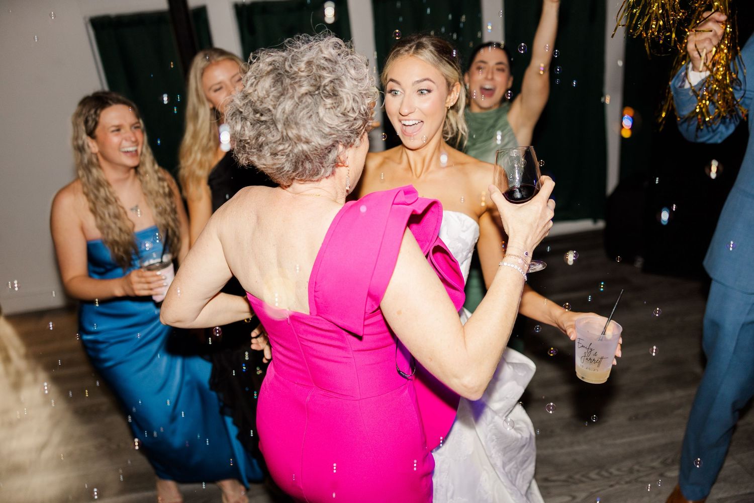 Wedding reception dance floor scene with guests in bright formal attire.