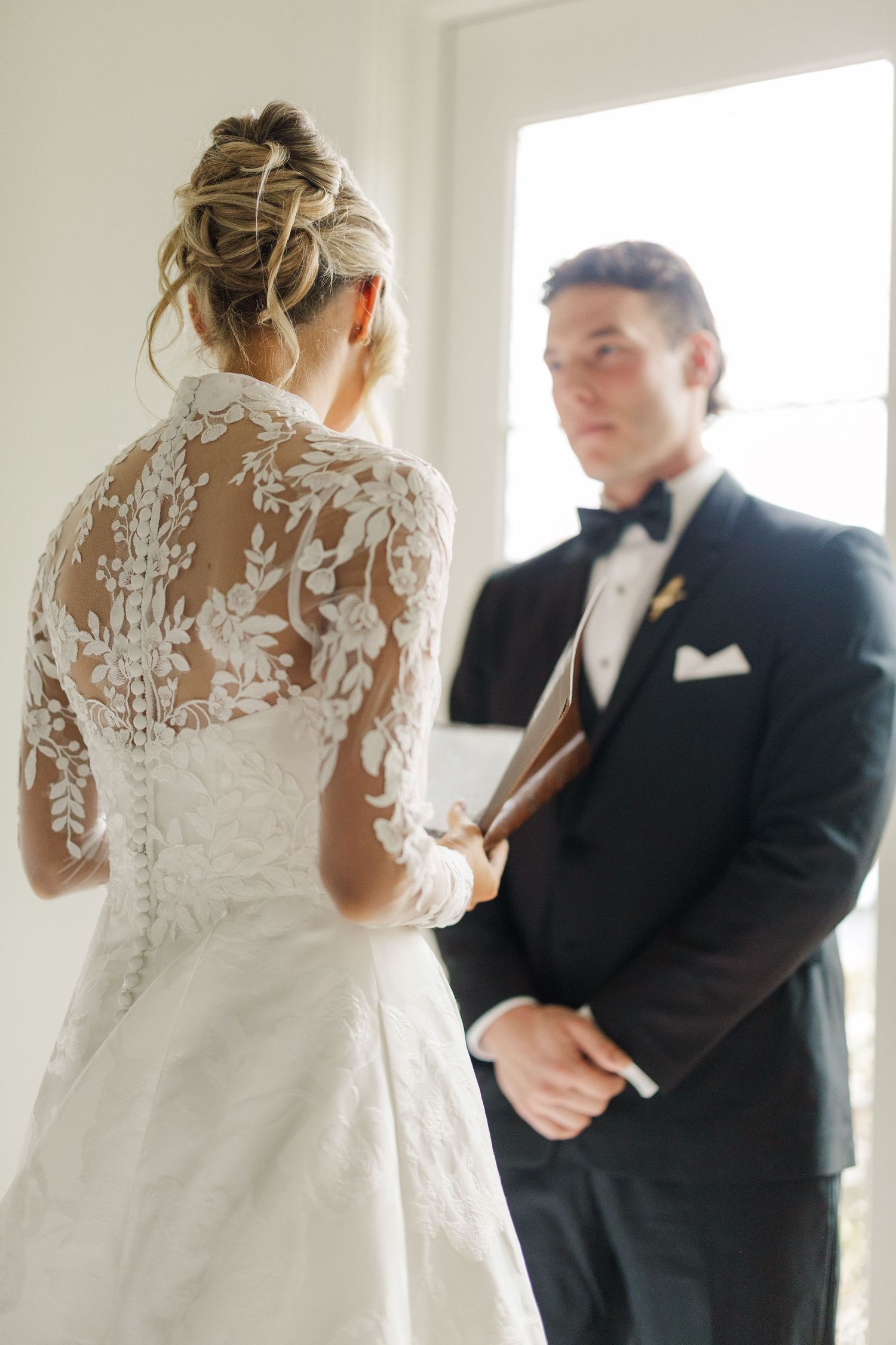 A tender first look moment between a couple on their wedding day in a bright white room.
