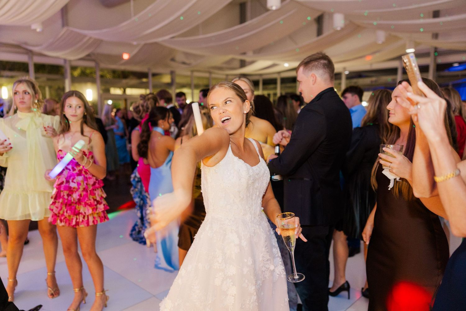 Wedding reception dance floor filled with guests celebrating and dancing.